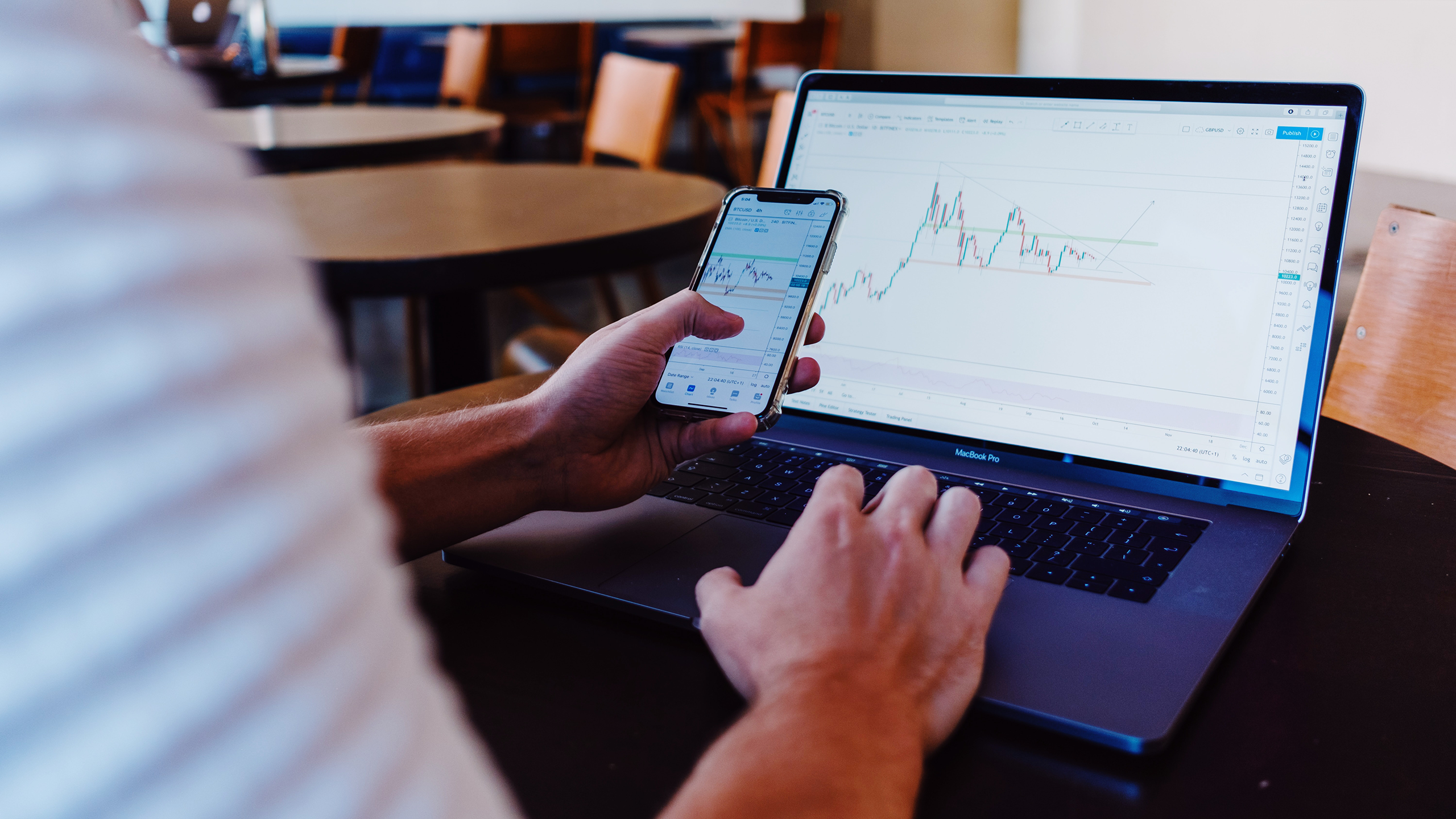 Person looking at stocks on their phone and laptop