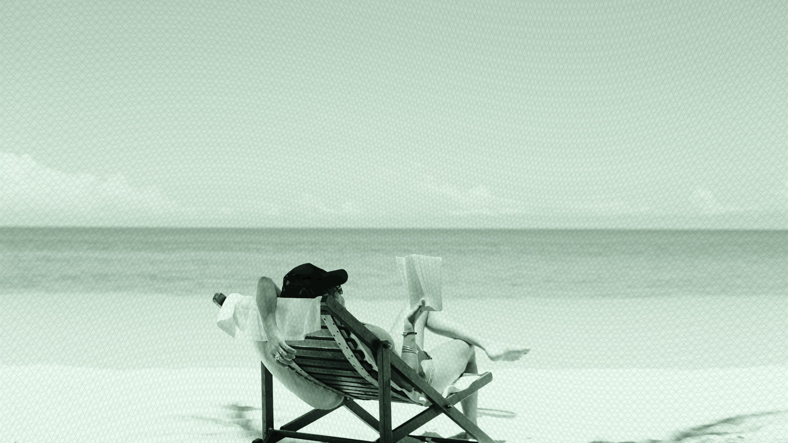 a woman sitting on the beach, reading a book.