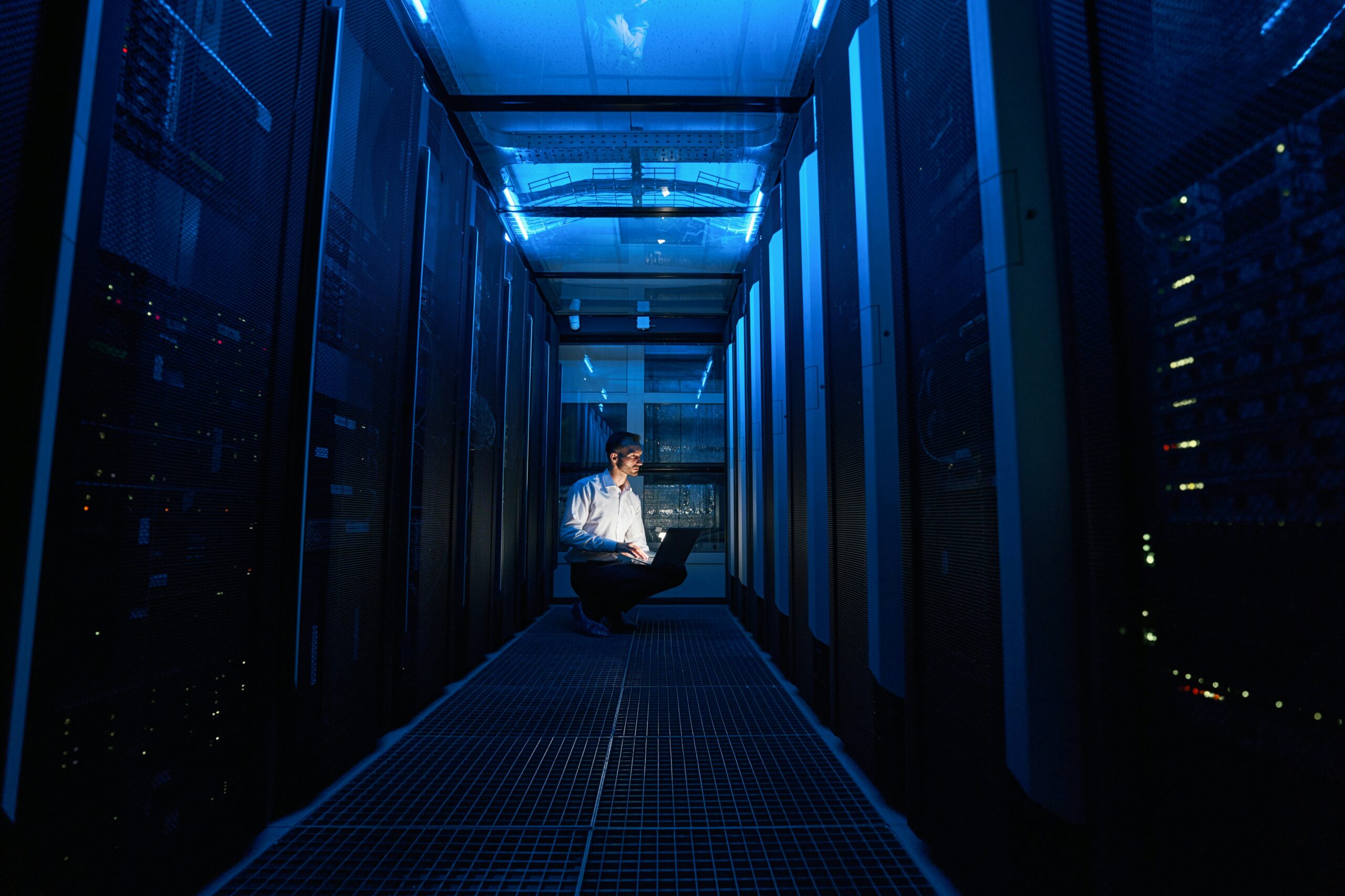 Person on a computer amid server racks.