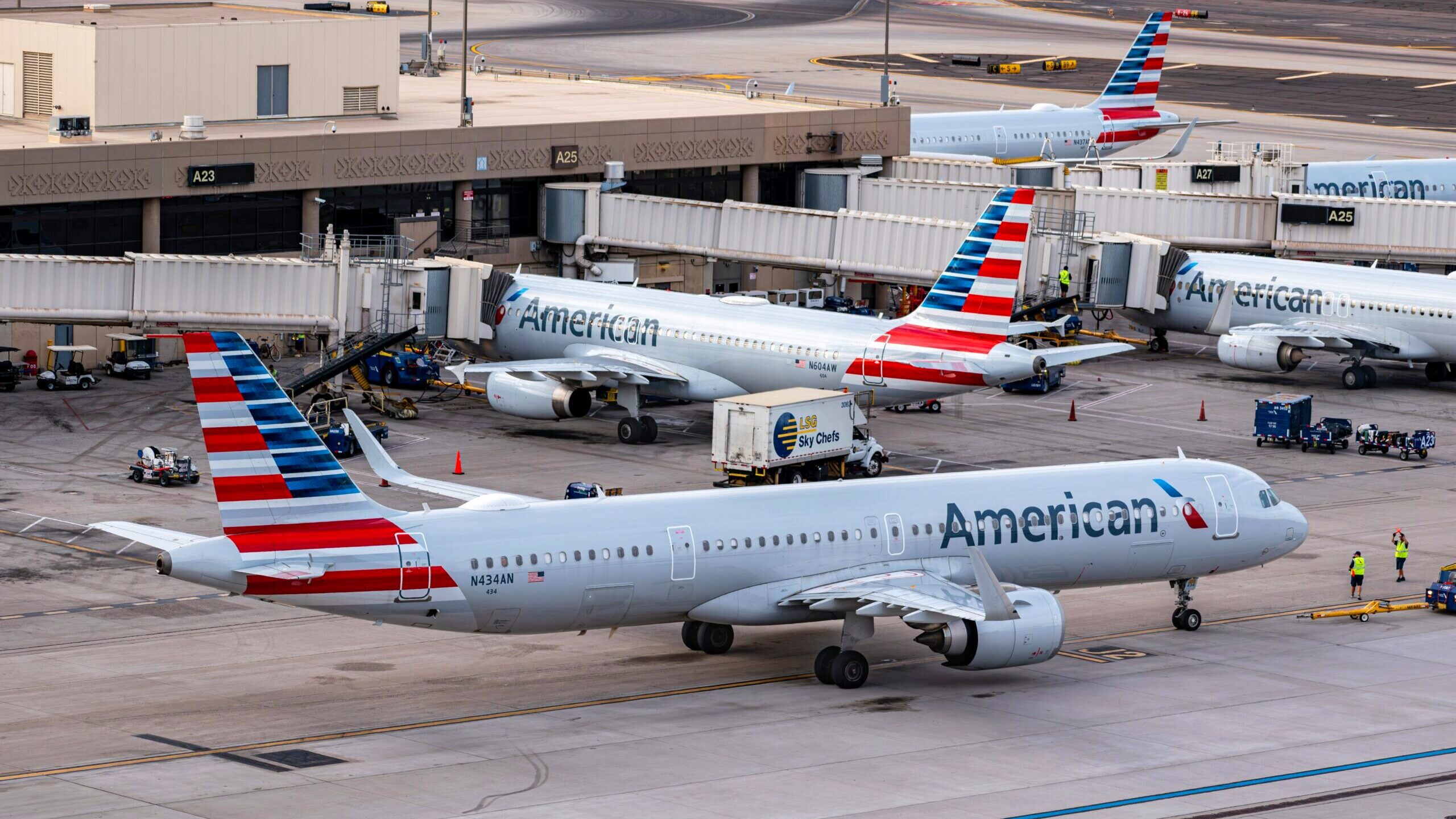 Several American Airline passenger jets are parked at an airport gate.
