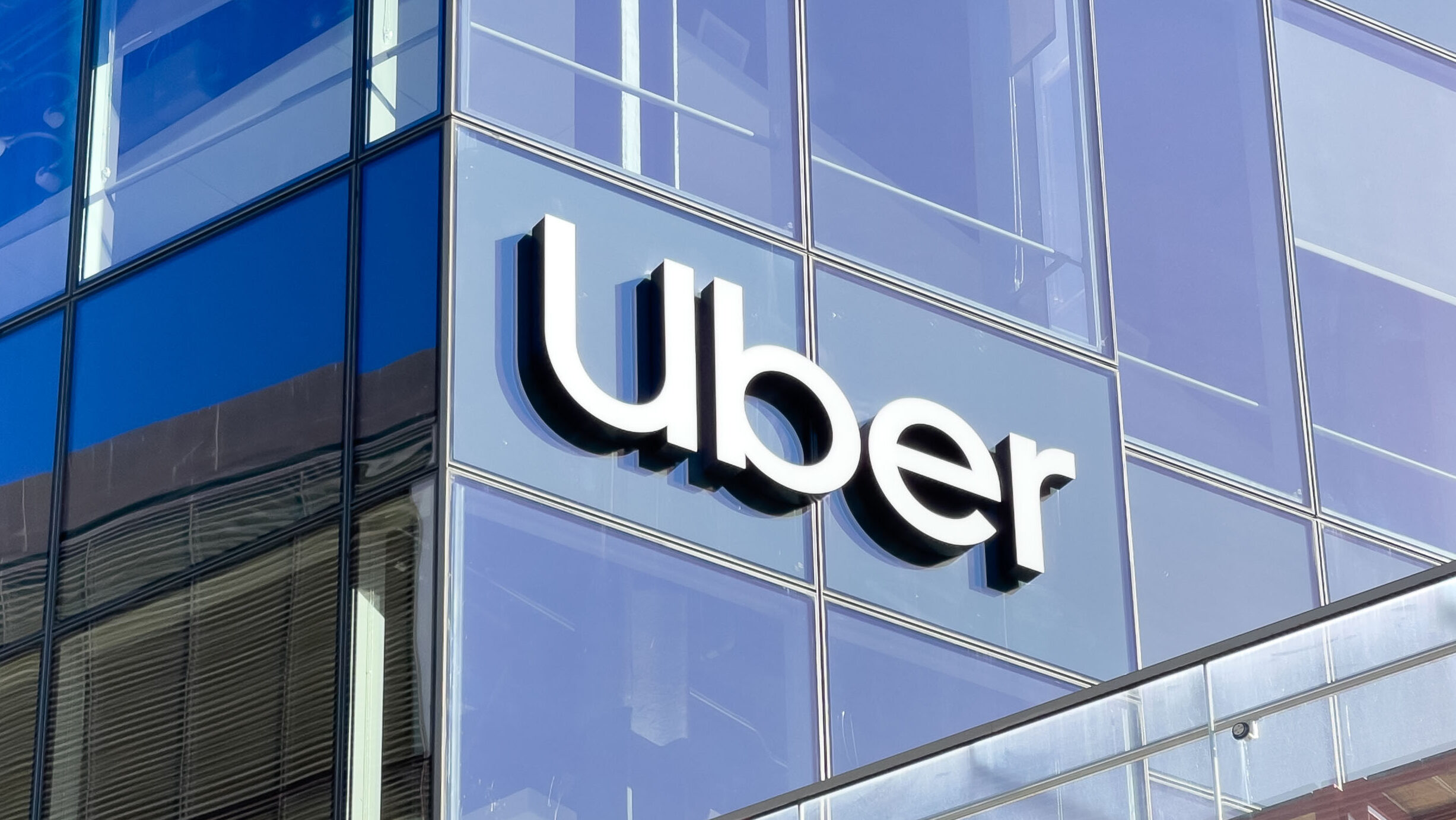 The Uber logo is shown on a glass window at the company's San Francisco headquarters.