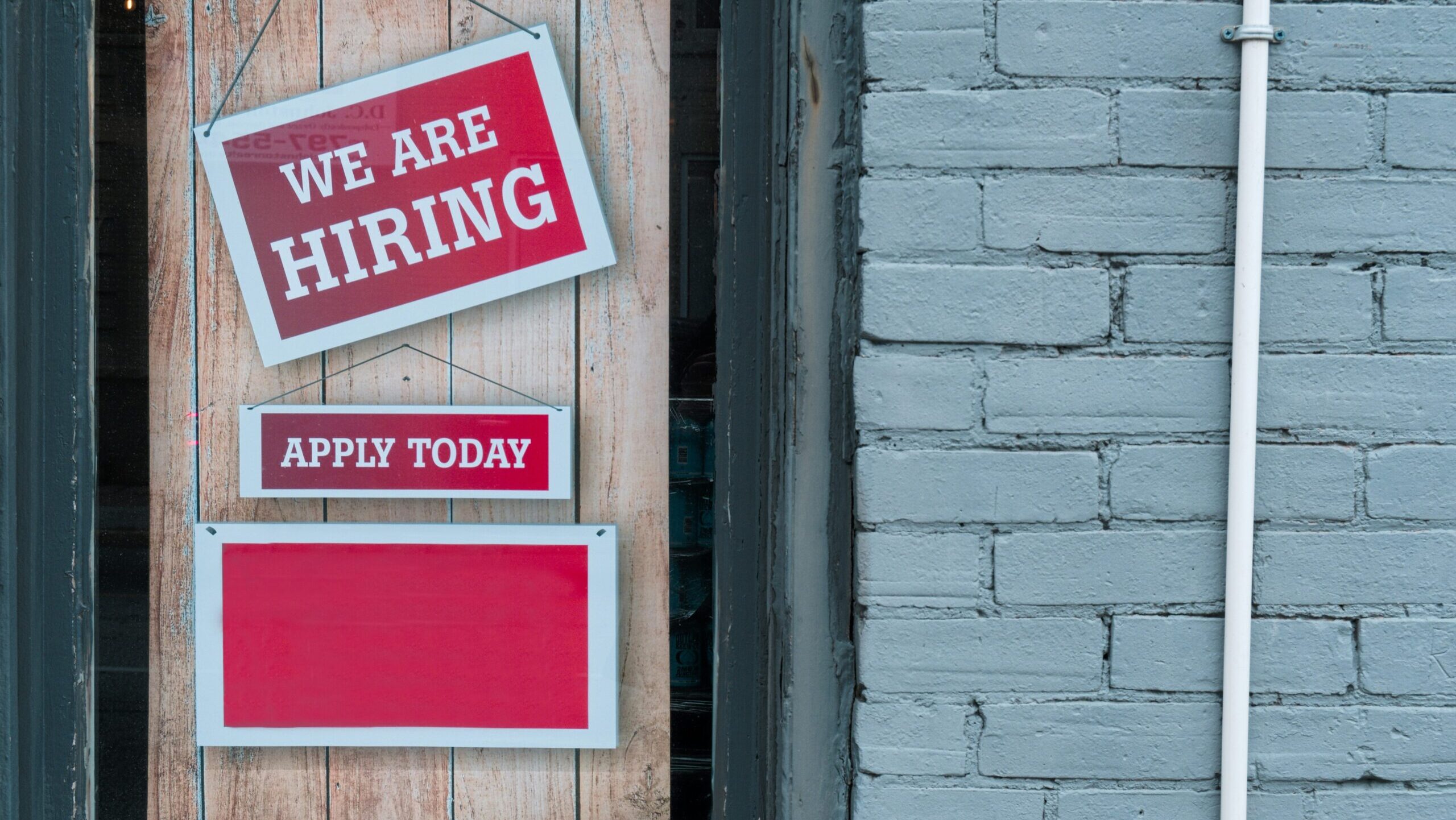 A sign in a door says "We are Hiring."