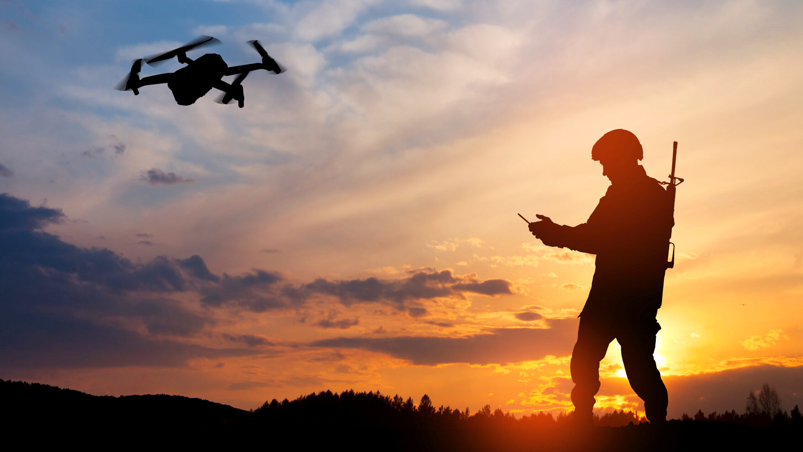 The silhouette of a soldier controlling a drone with a handheld device is shown in front of a sunset.