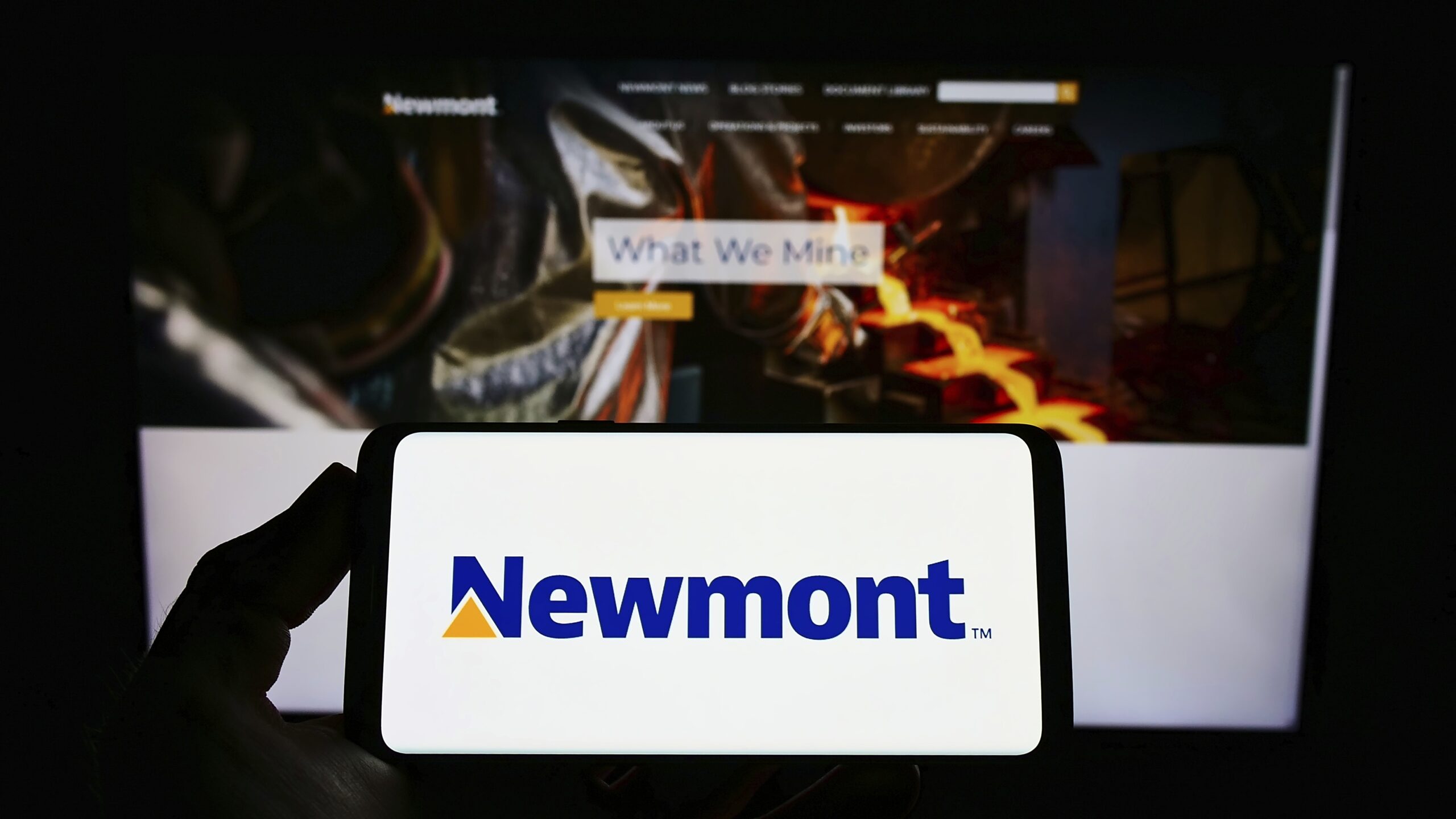 A person holds a mobile phone with the logo of American gold mining company Newmont Corporation on its screen.