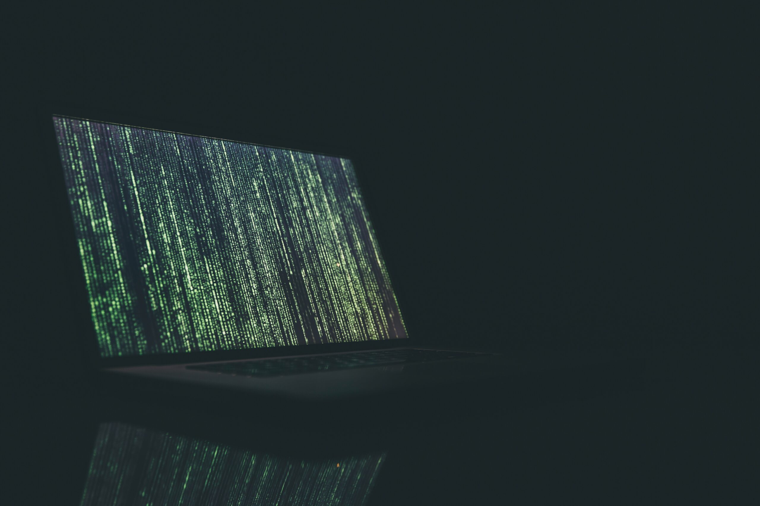 Photo of code on a computer screen in a dark room.