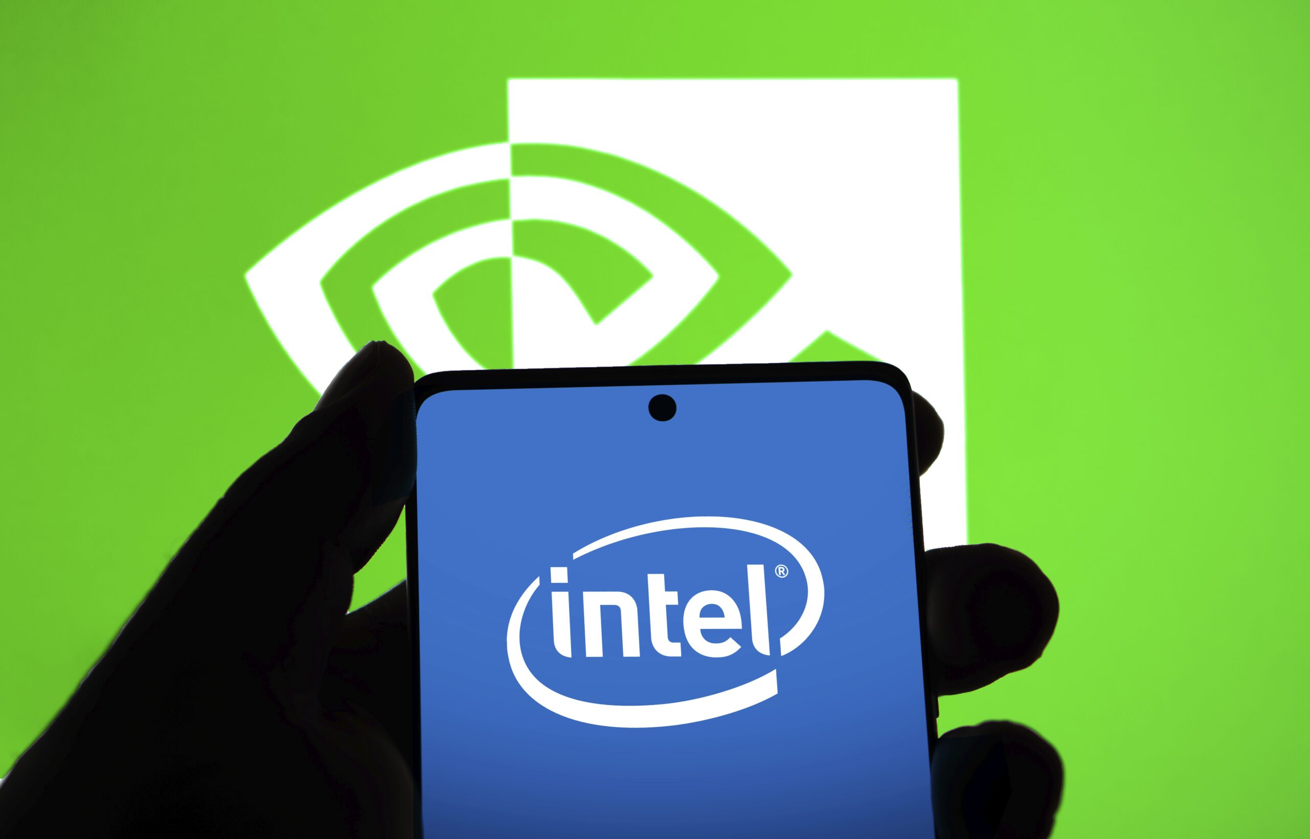 The Intel logo is displayed on a phone screen in front of the Nvidia logo.