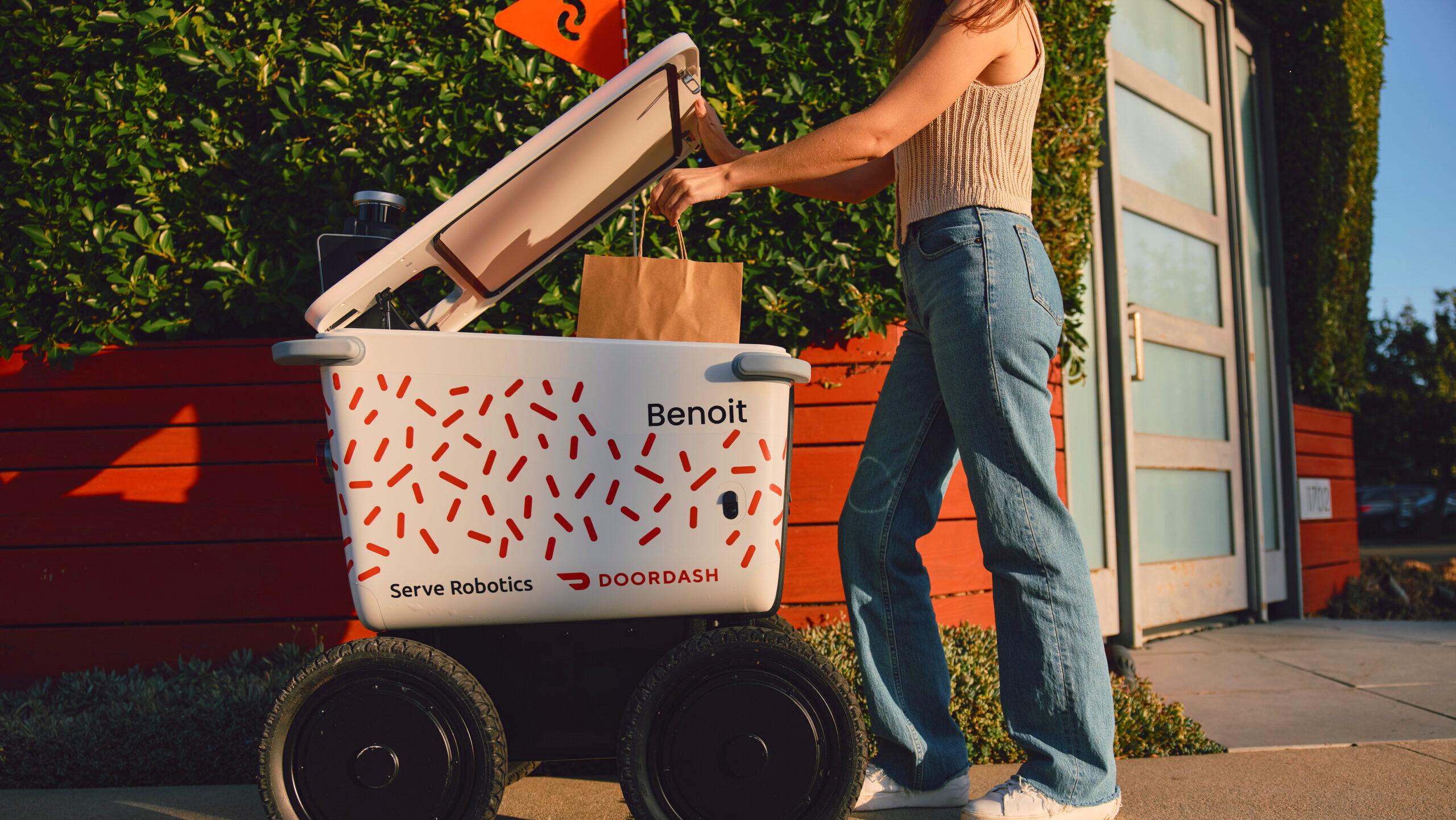 Image of a woman receiving a DoorDash order from a Serve Robotics robot.