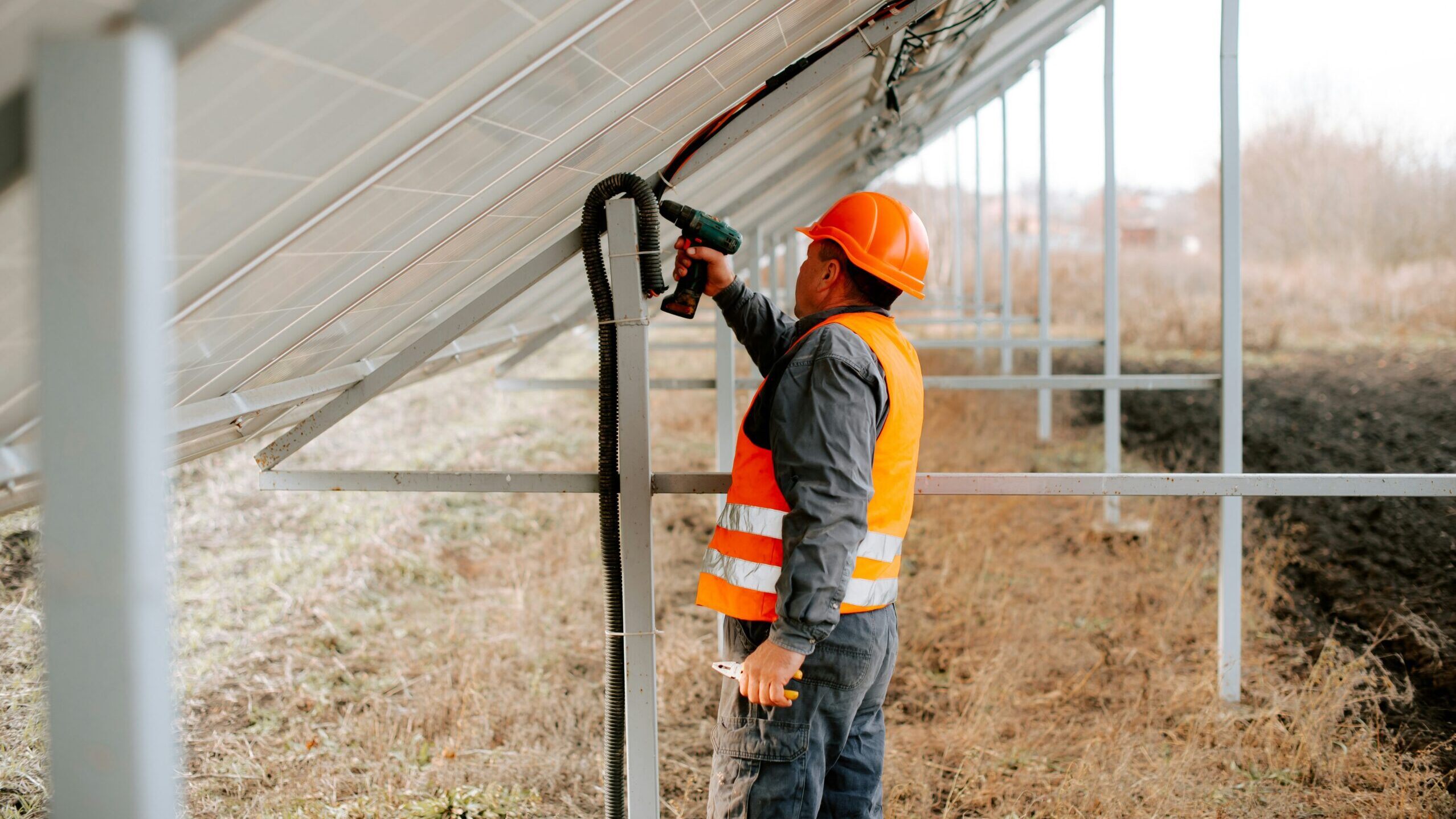 A worker is seen using a power drill to install a solar panel.