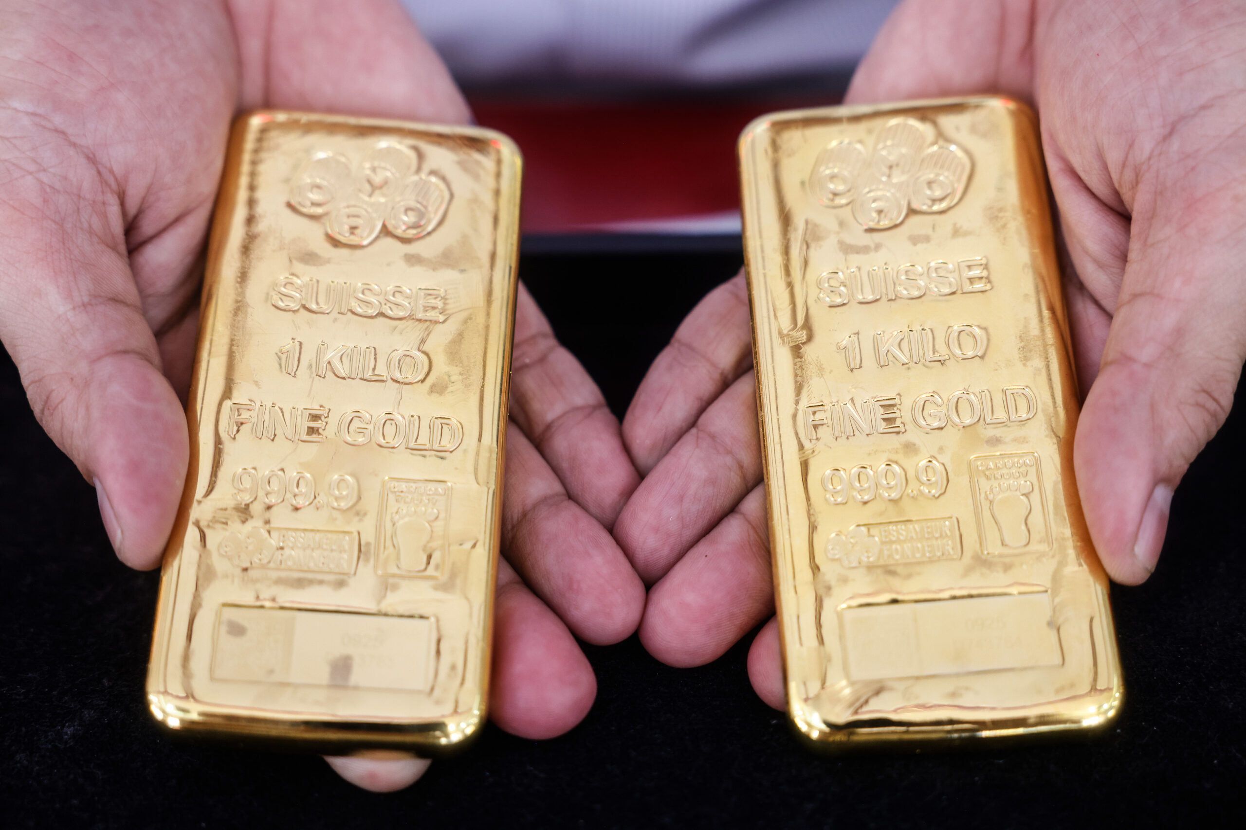 Hands holding two gold bars.