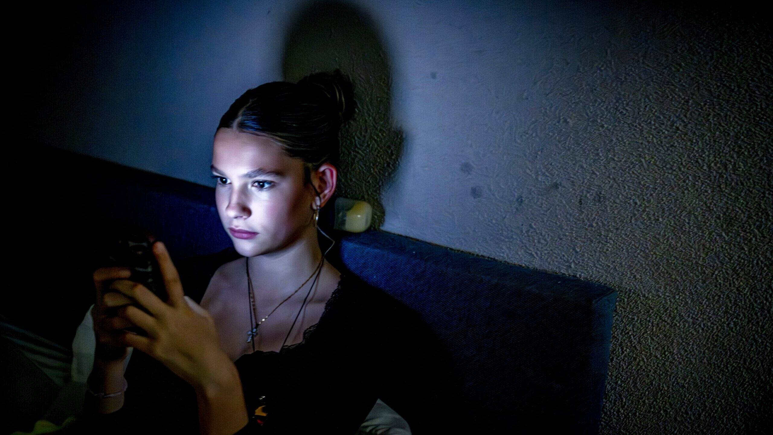 Photo of a teenage girl scrolling on her smartphone.