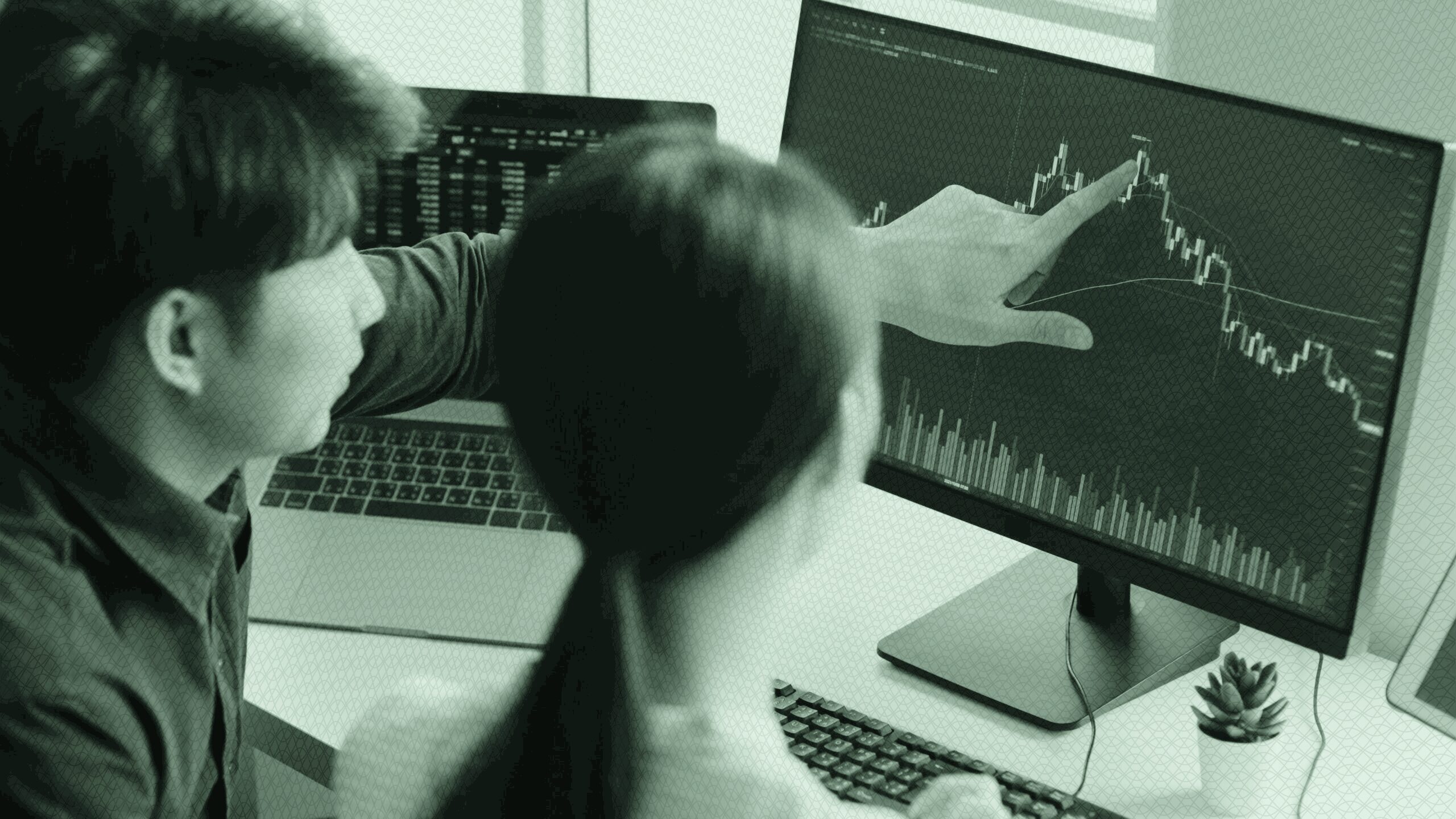 Two people looking at stocks on a computer.