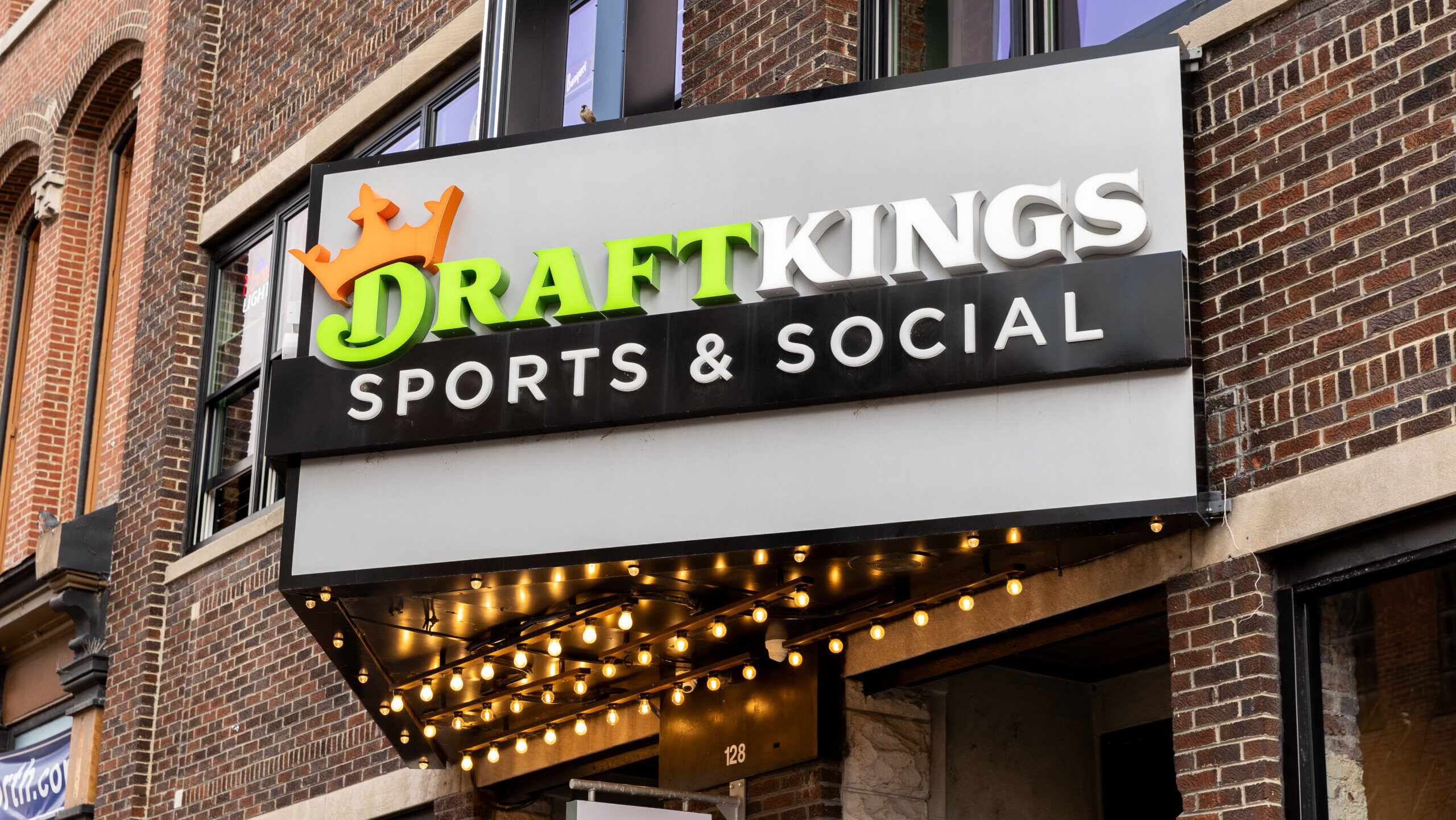 A DraftKings Sports and Social location in Nashville, viewed from outdoors, bears the company's logo on a marquee display.