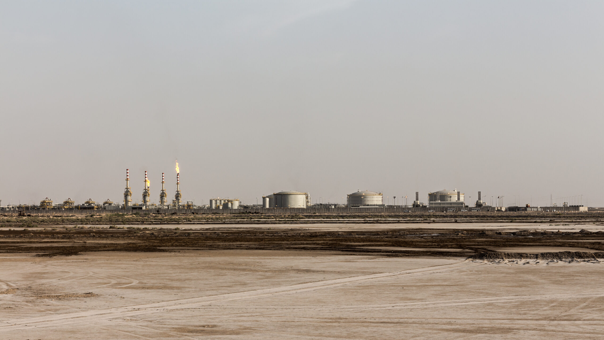 An oil and gas refinery in Iraq is seen from a distance across open landscape.