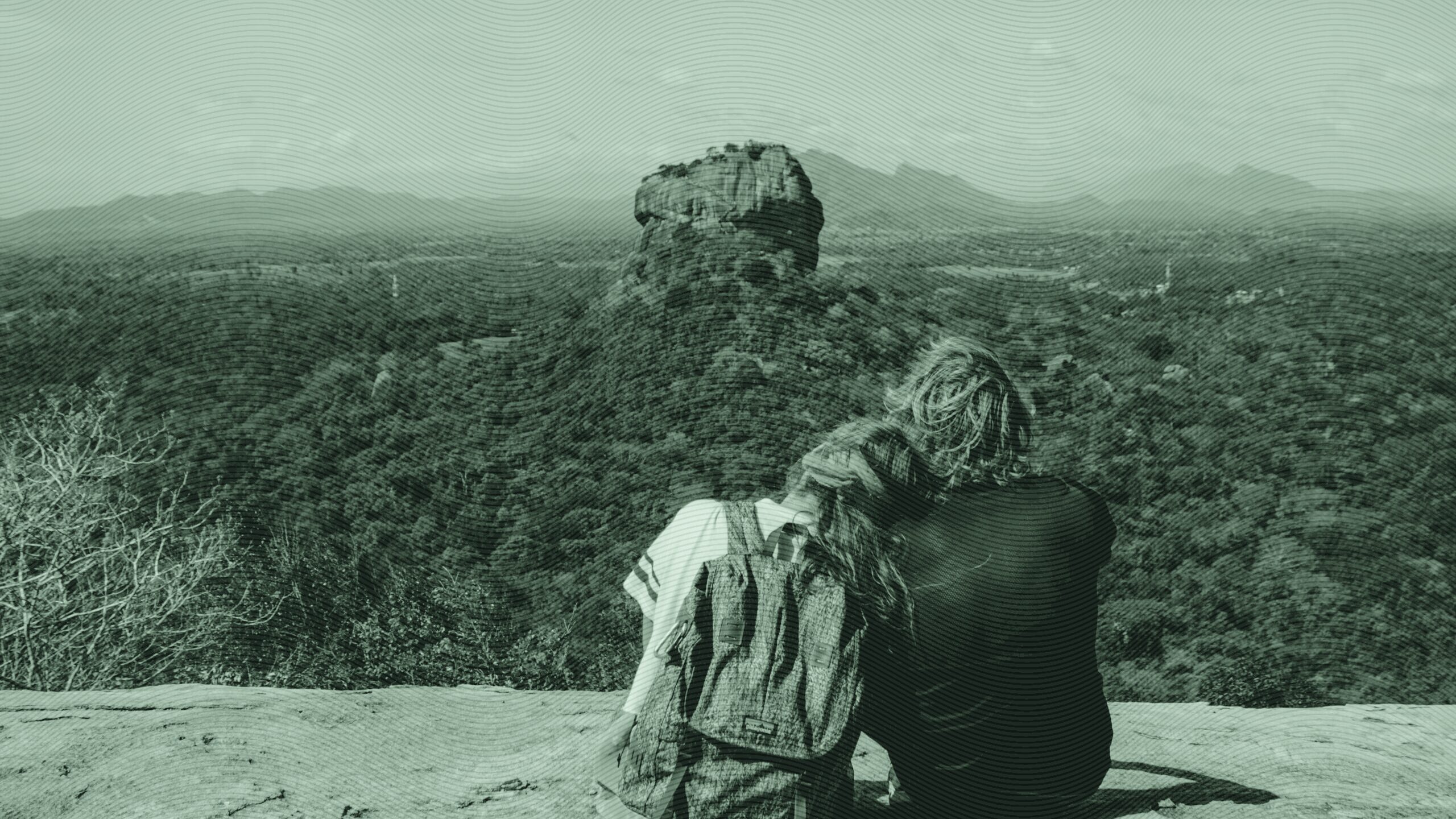 A couple sitting on a cliff.