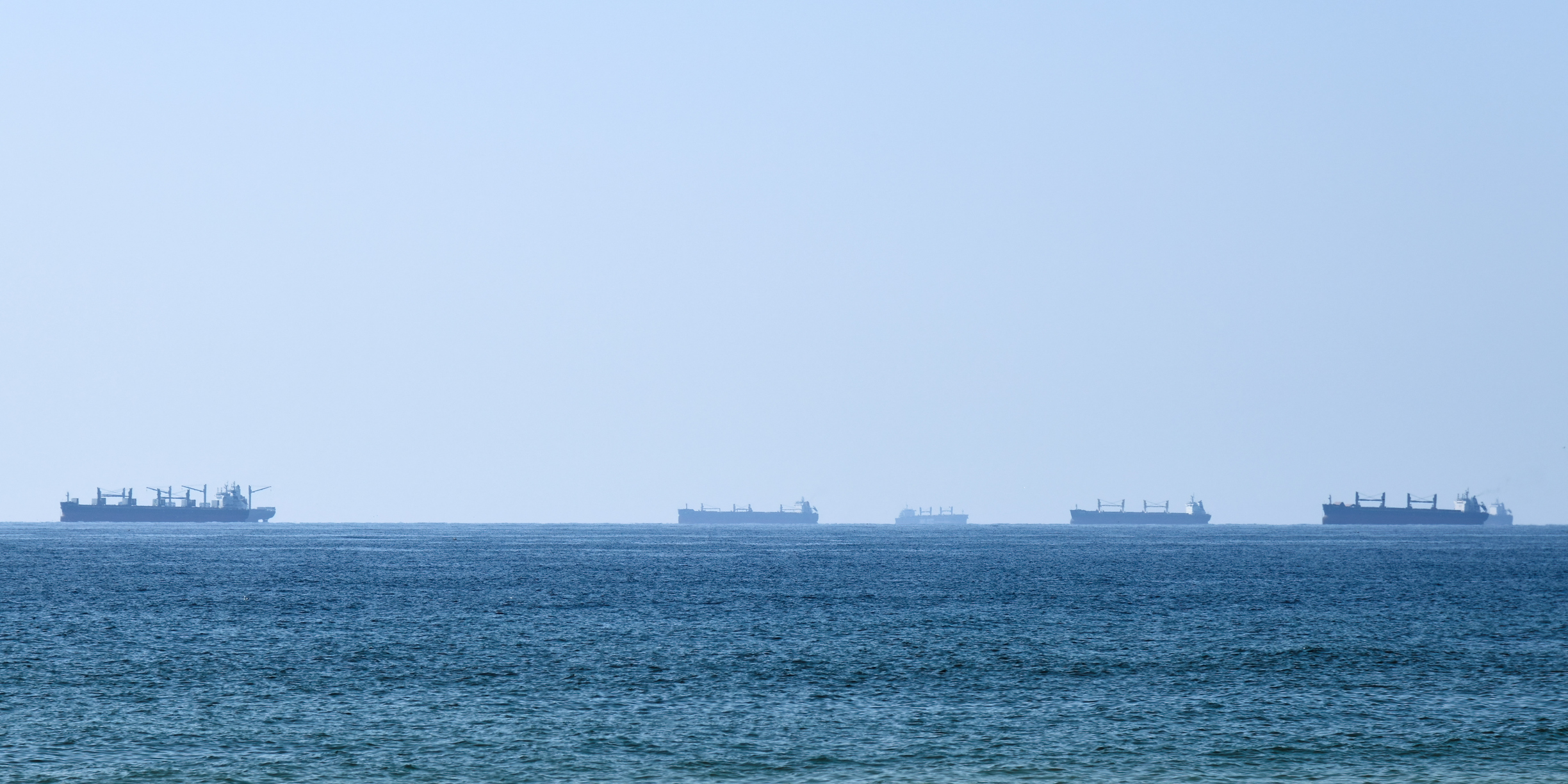 A silhouette of cargo ships line the horizon in Hormuz as seen from Oman.