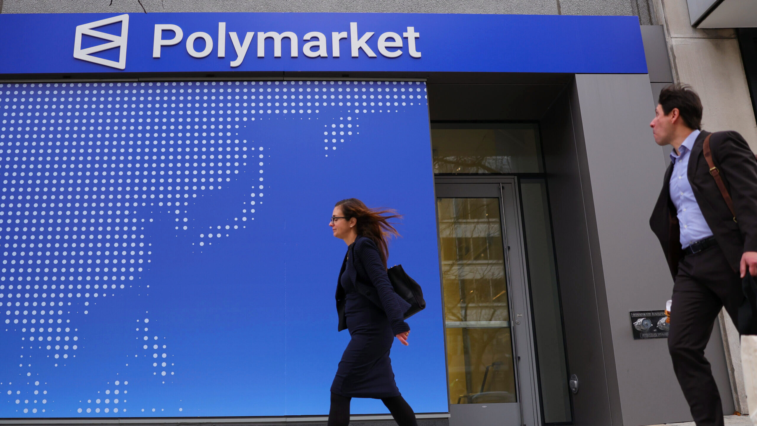 Photo of people walking past a Polymarket sign.