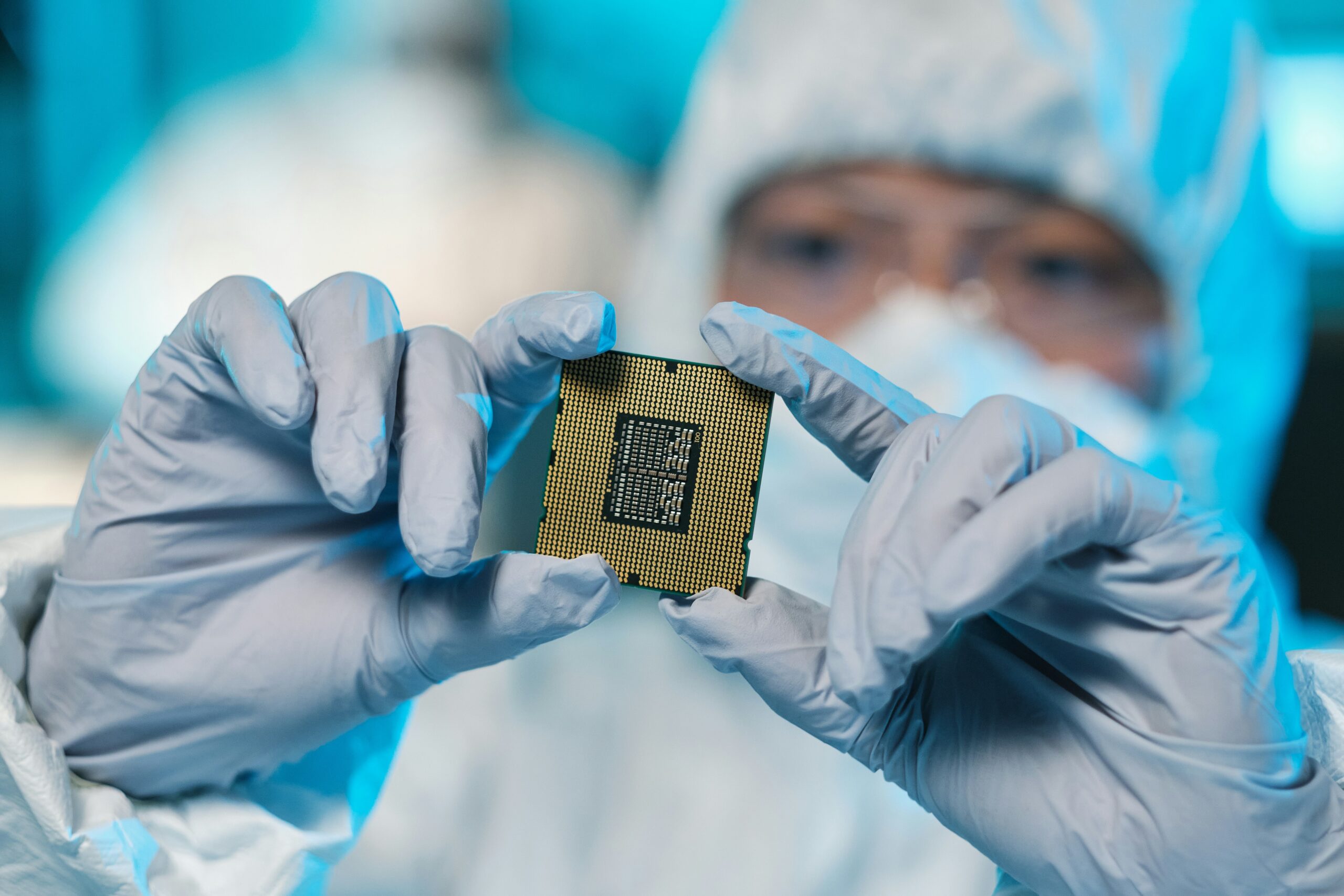 Worker in white suit holding a silicon chip.