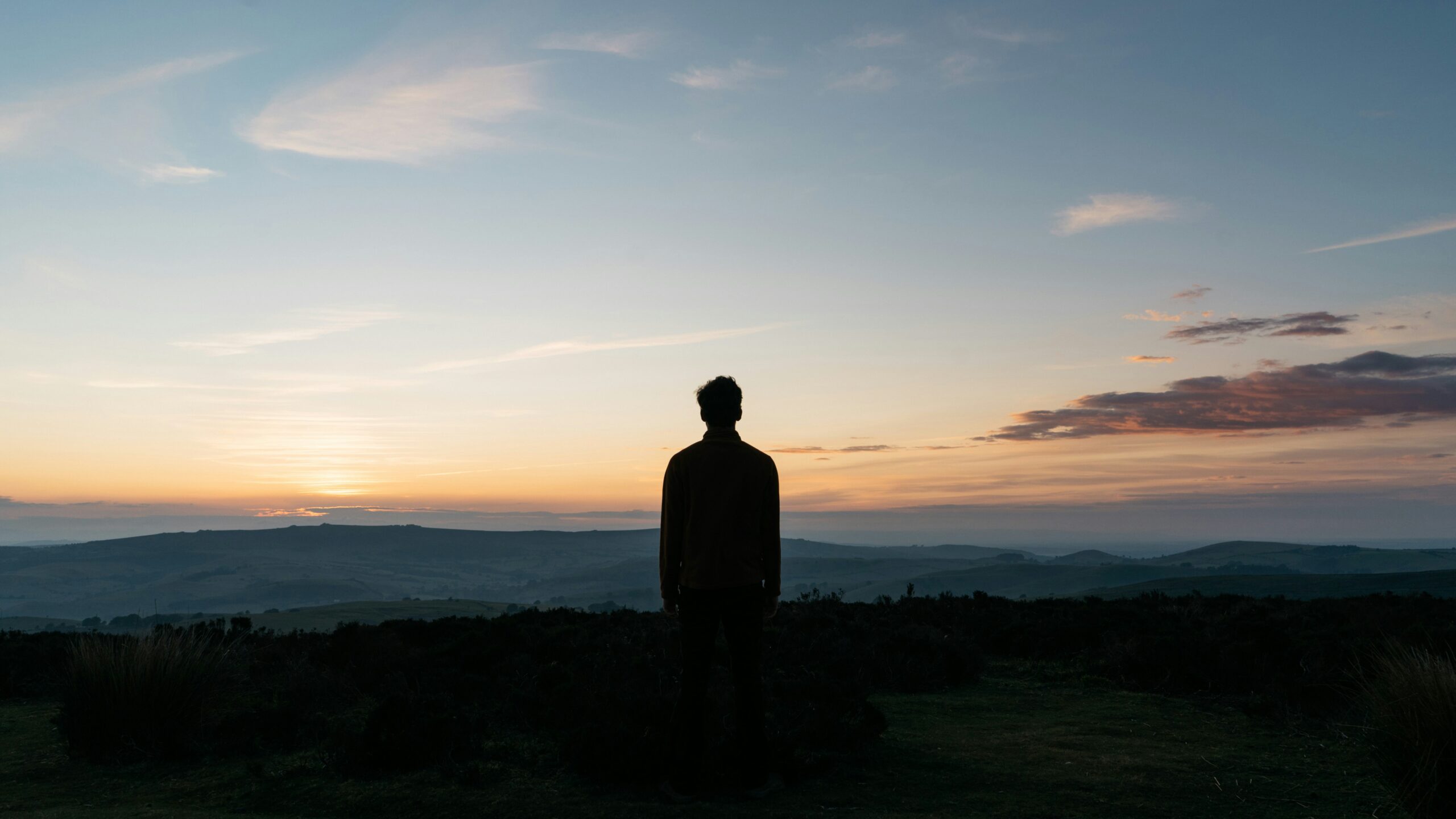 Silhouette of single person standing against a dark background.