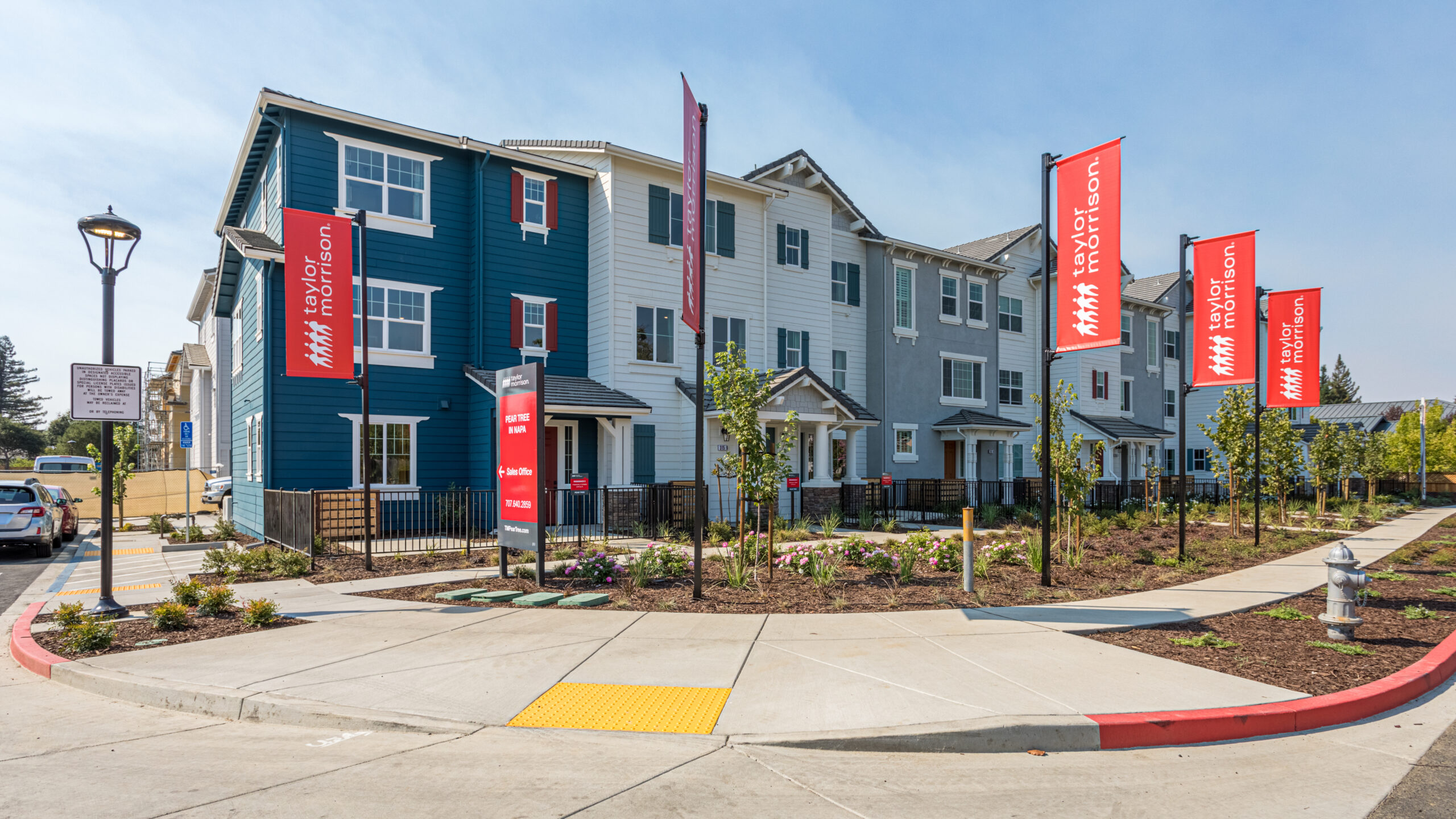 A group of row houses are shown on a street in Napa, California, with a sign pointing to a Taylor Morrison sales office.