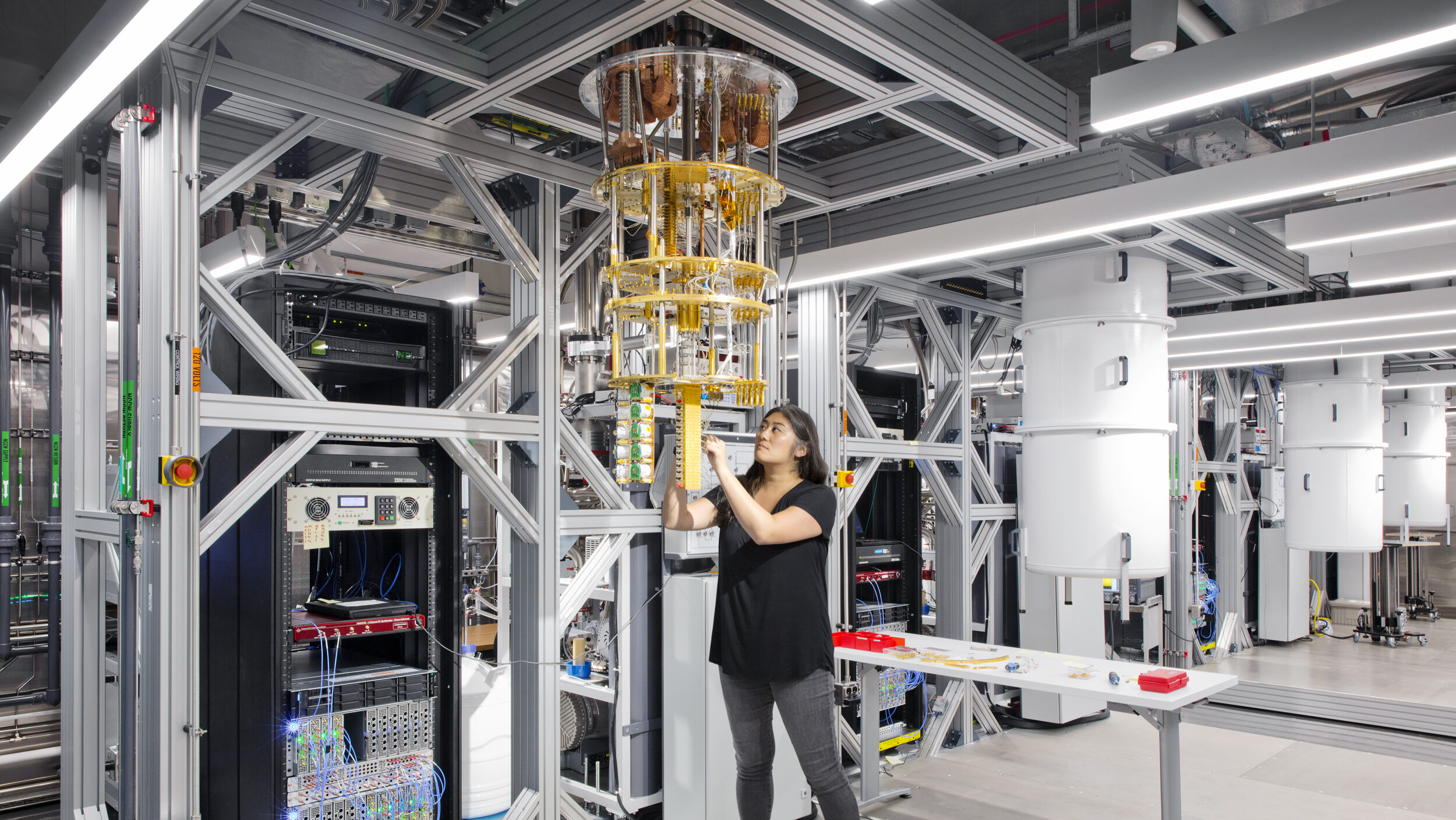 IBM Quantum scientist Dr. Maika Takita is shown in a lab with quantum computer parts.