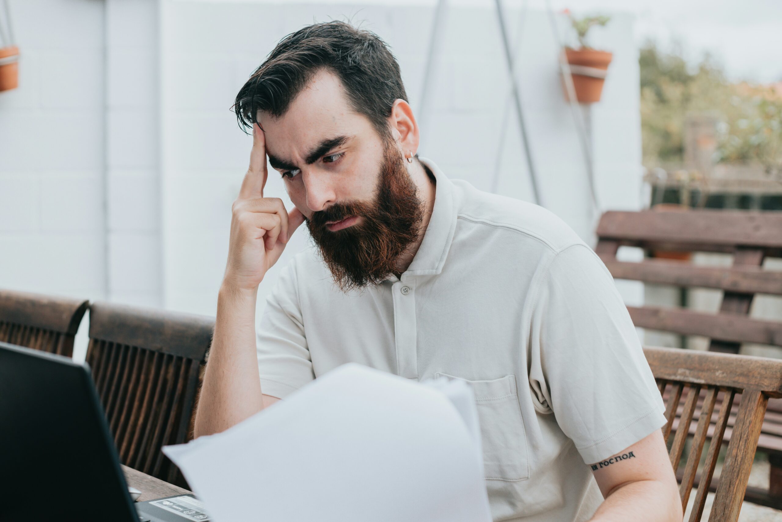 Man with large beard reading a document and appearing concerned.