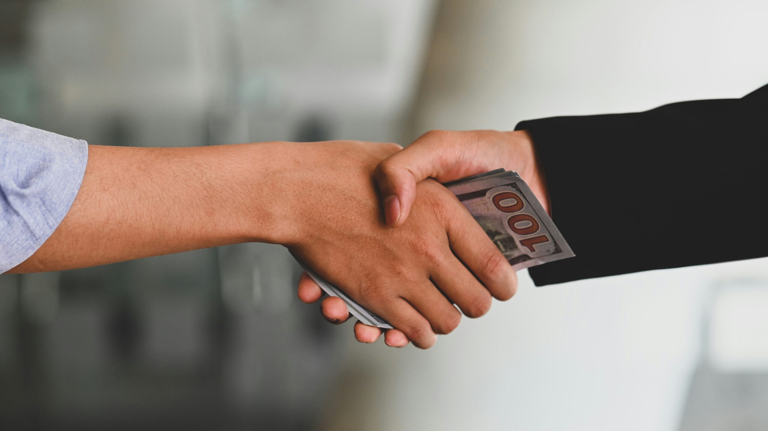 Photo of people shaking hands with money