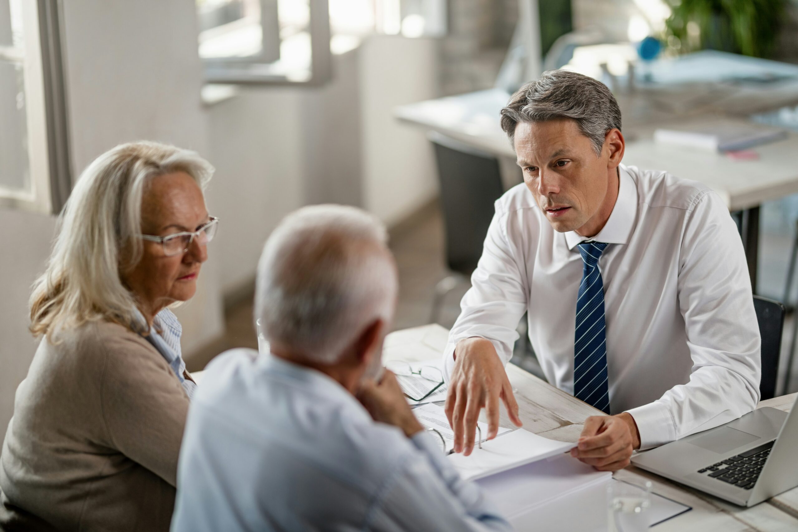 Group of three people sitting at a desk discussing documents.