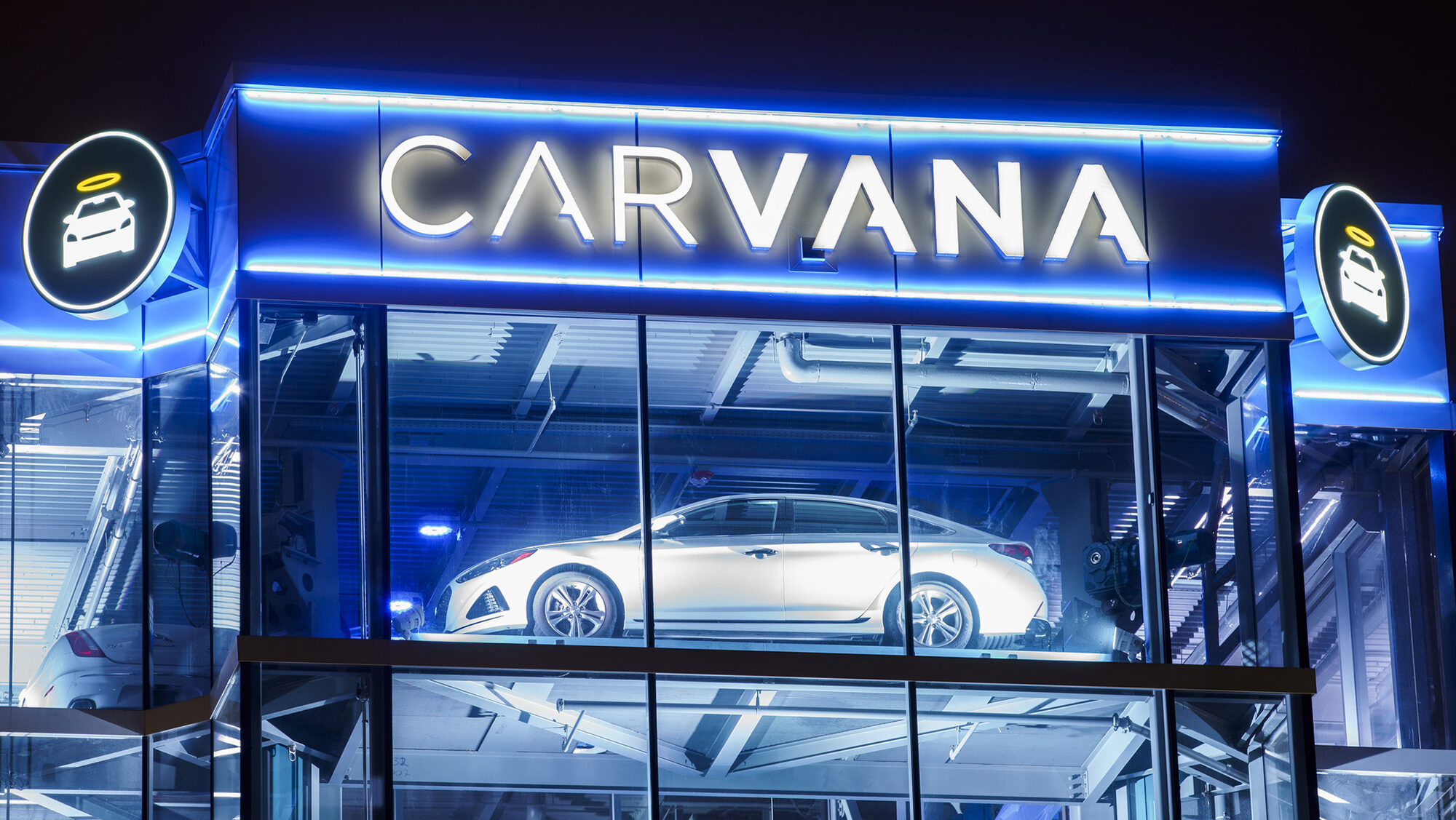 An illuminated Carvana glass tower is shown at night in Oak Brook, Illinois.