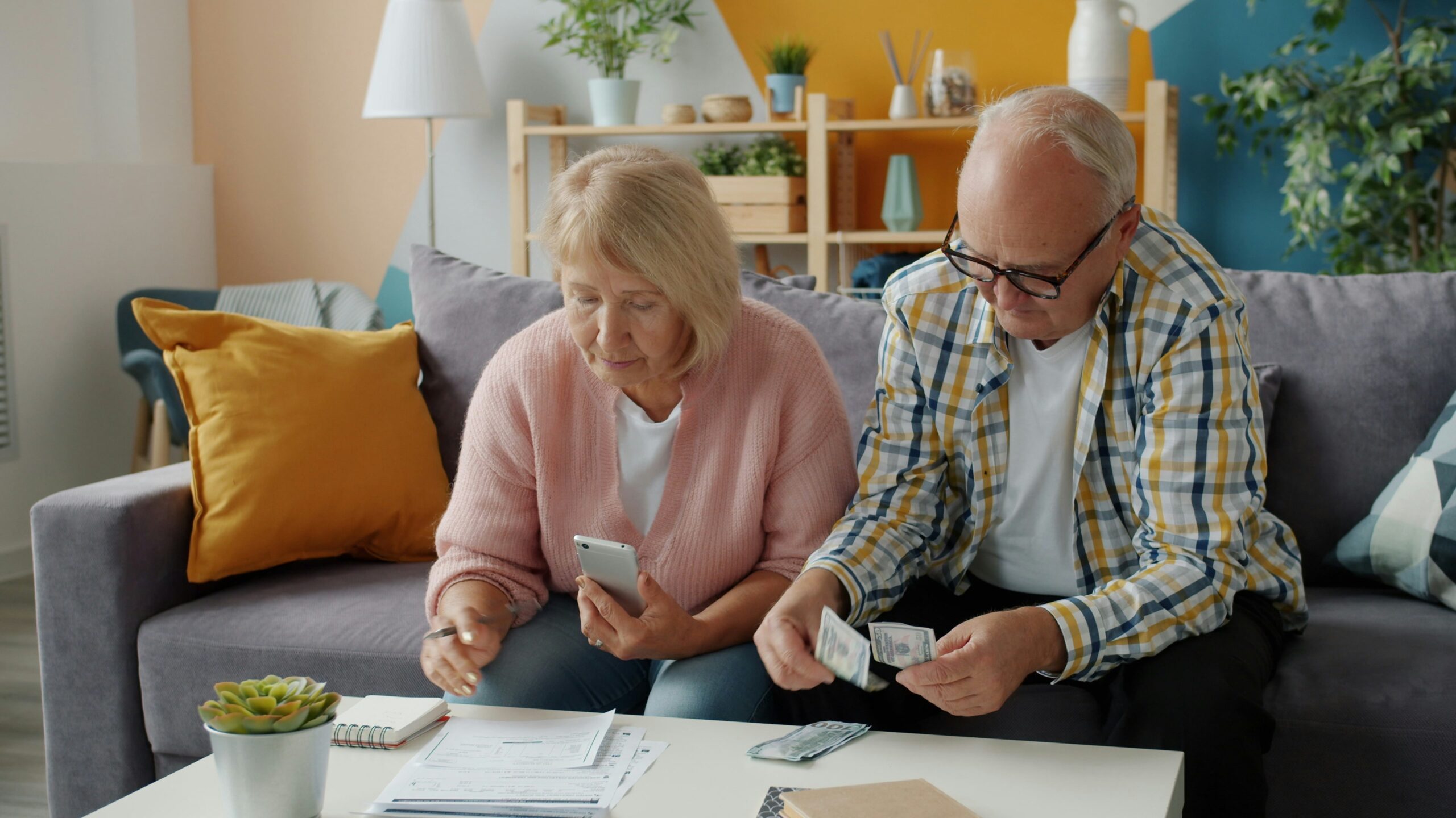 Photo of older couple counting out money and checking documents on a table.