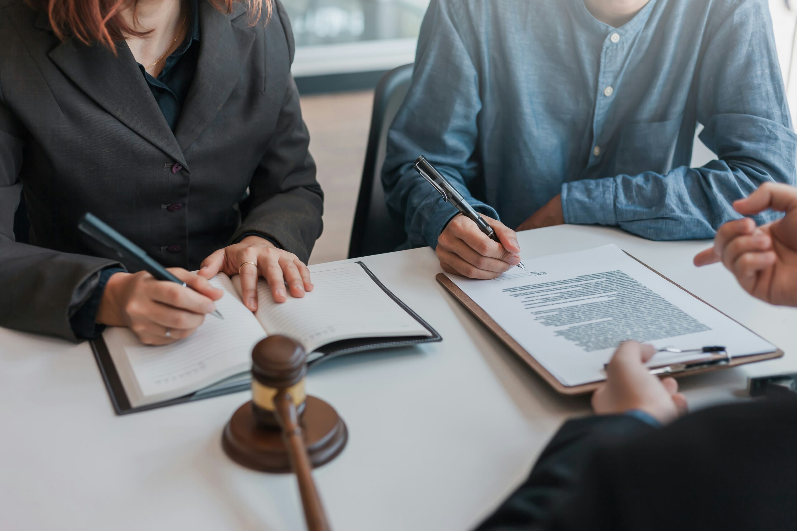 Photo of people sitting at a desk reviewing and signing legal documents.