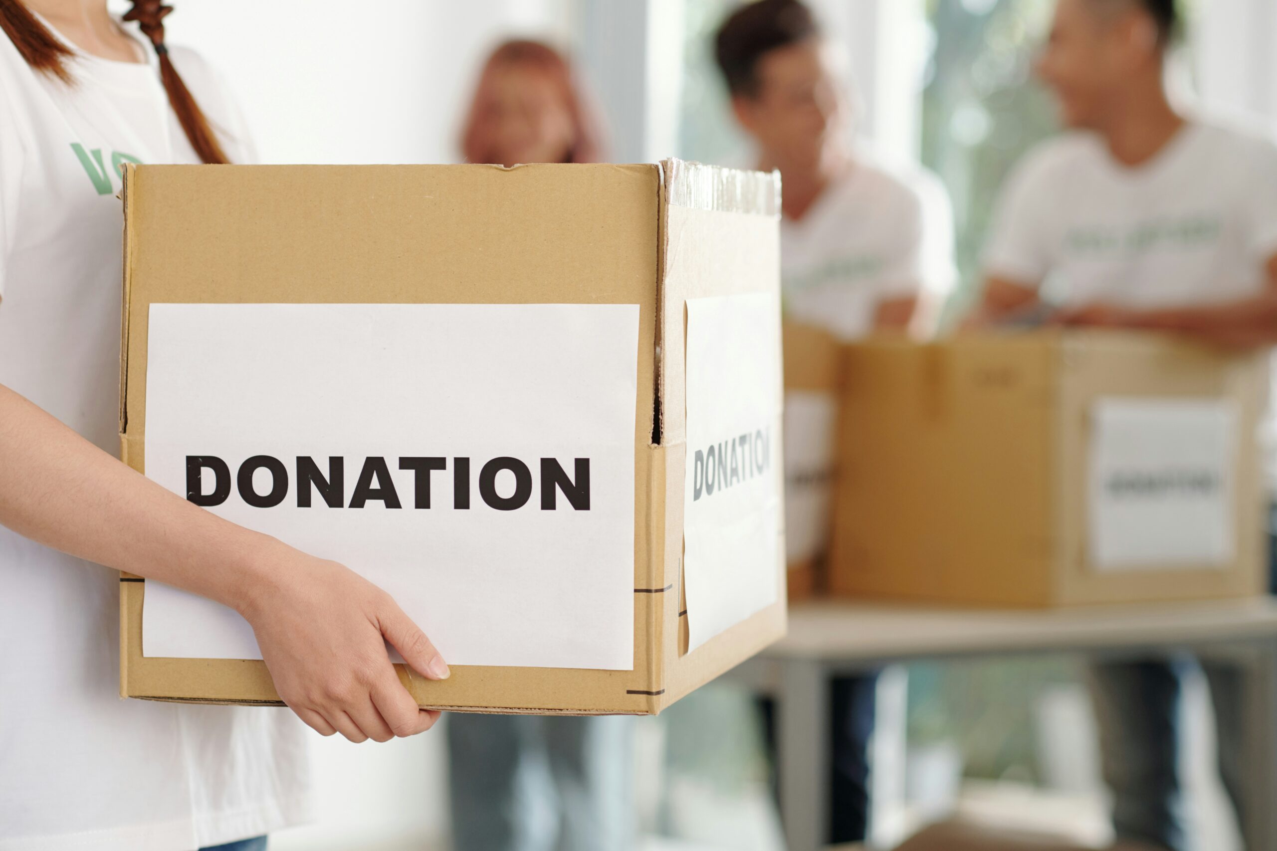 Photo of a person carrying a box with the word donation printed on the side.