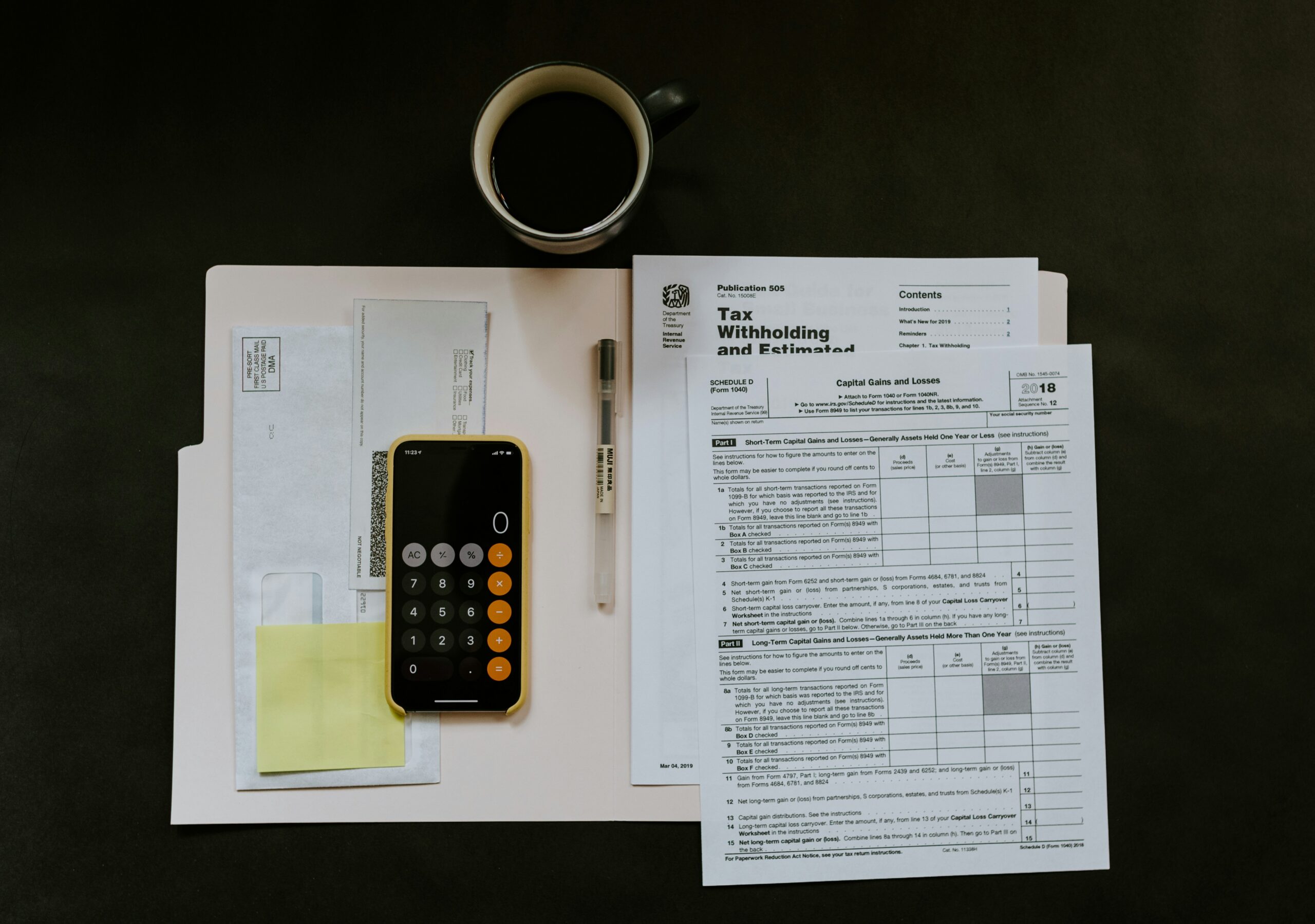 Photo of various tax forms, a cup of coffee and a calculator showing 0.