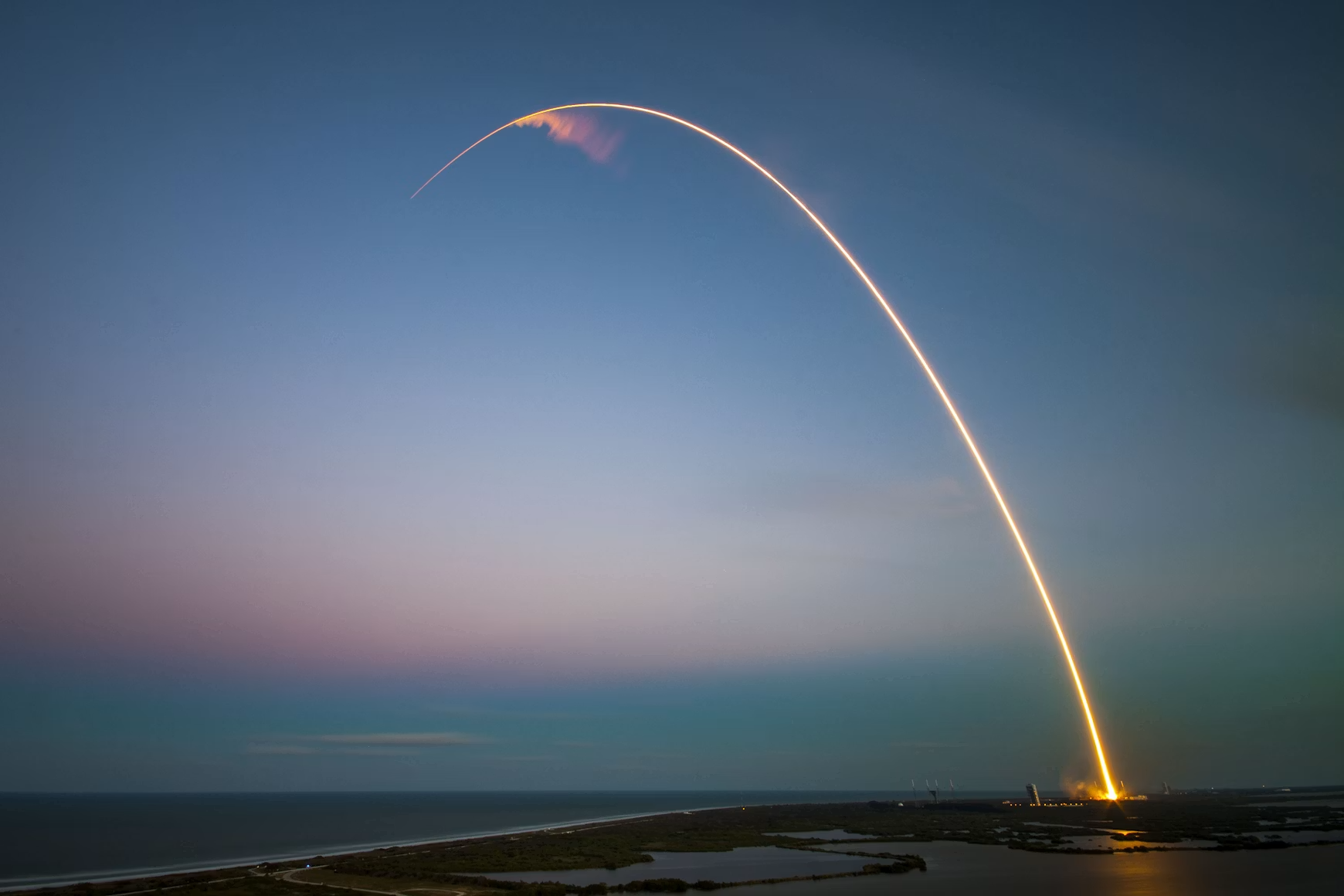 Photo of a rocket ship taking off into a dark blue sky.