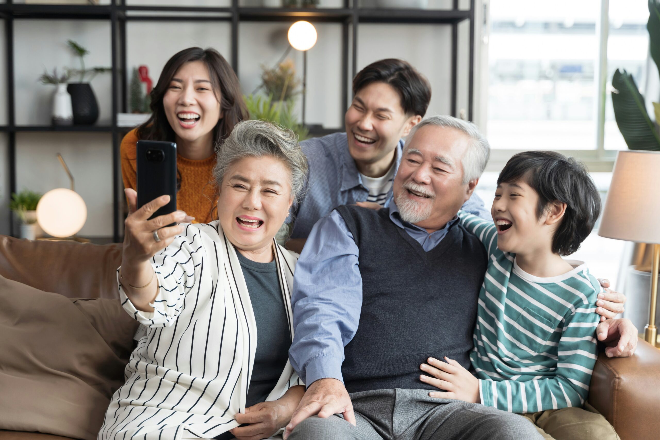 Photo of three generations of a family sitting together on a couch posing for a photo.