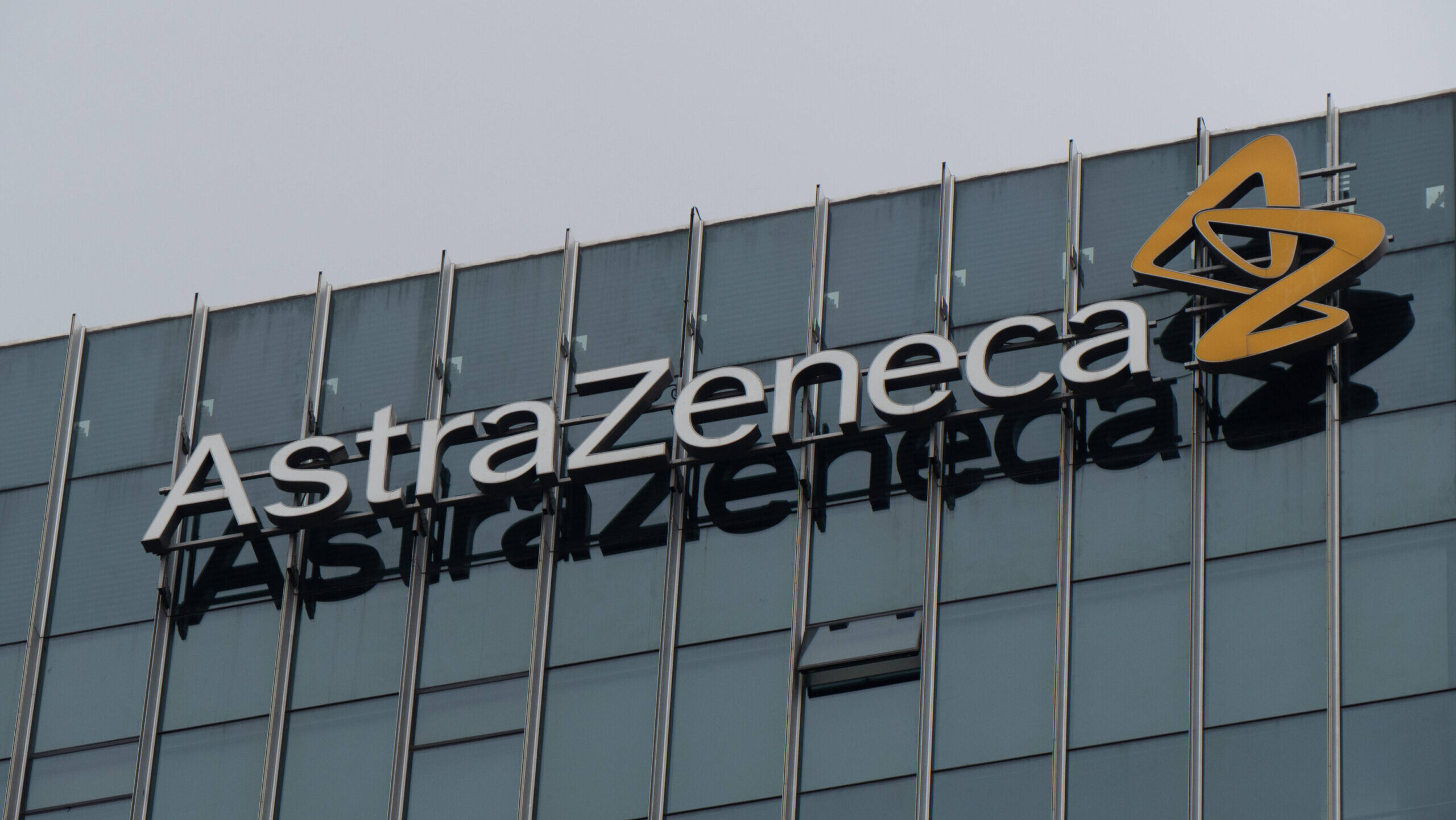 An AstraZeneca office building with the company's lettermark is shown.