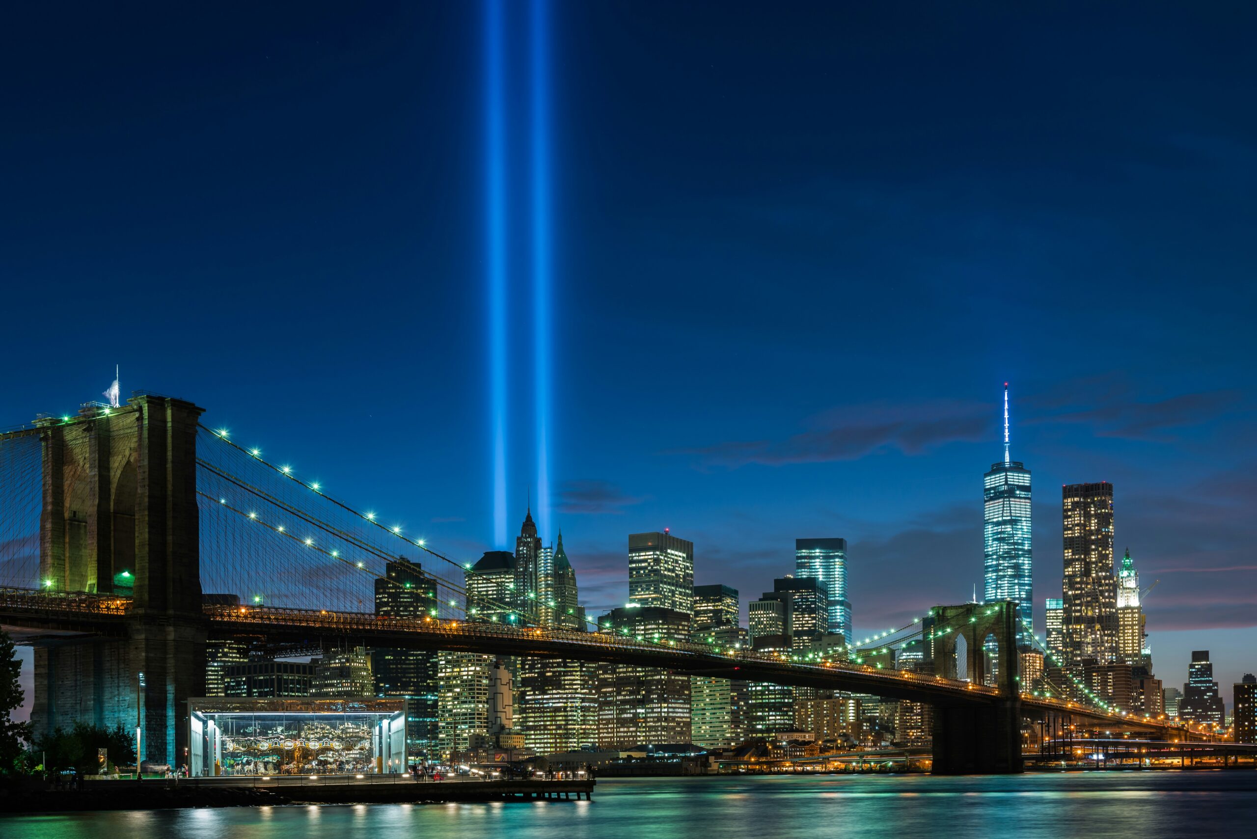 Photo of the New York city skyline with 9/11 memorial lights shining.
