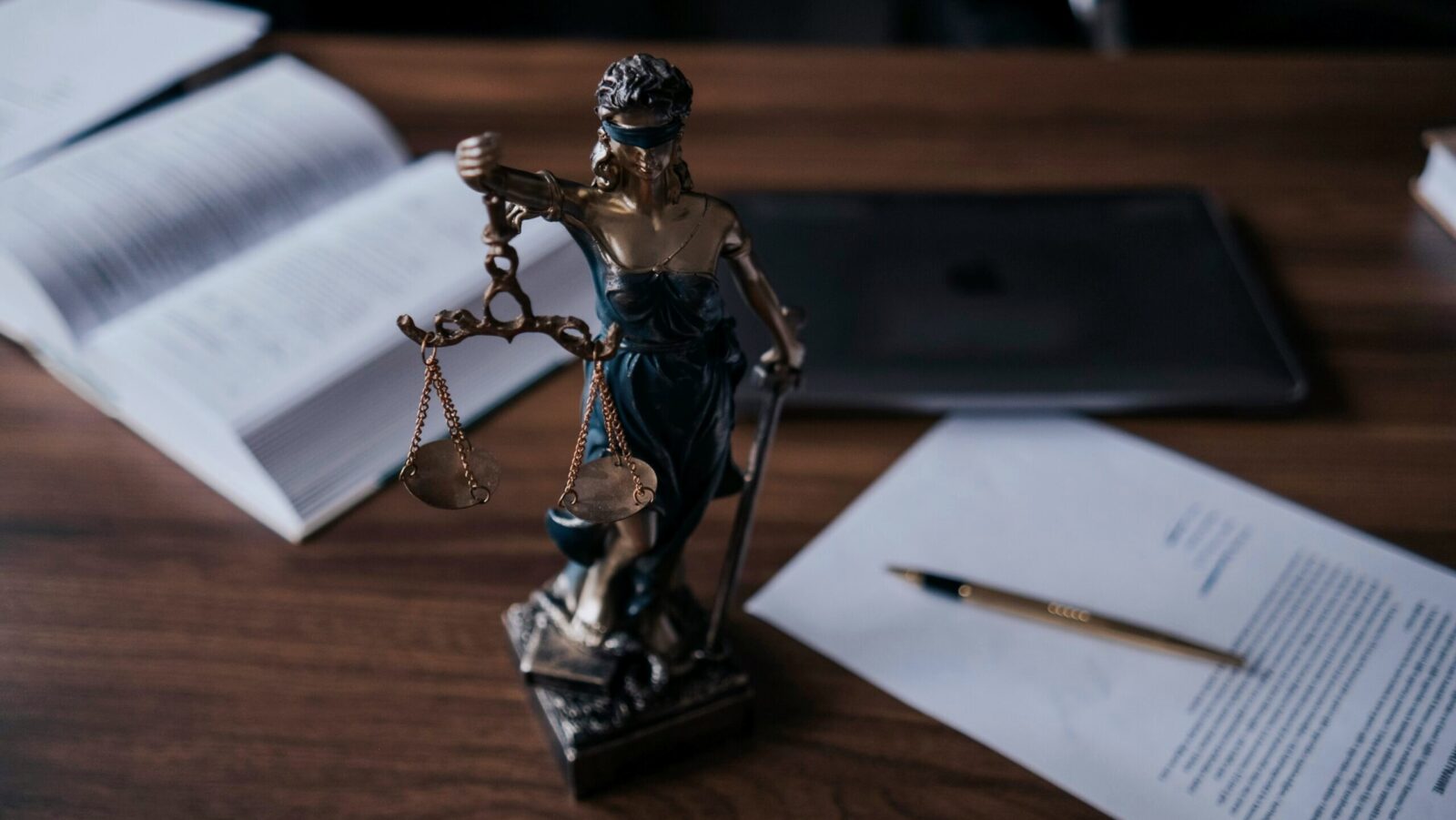 A small statue of Lady Liberty is shown on a work desk next to papers and a laptop.