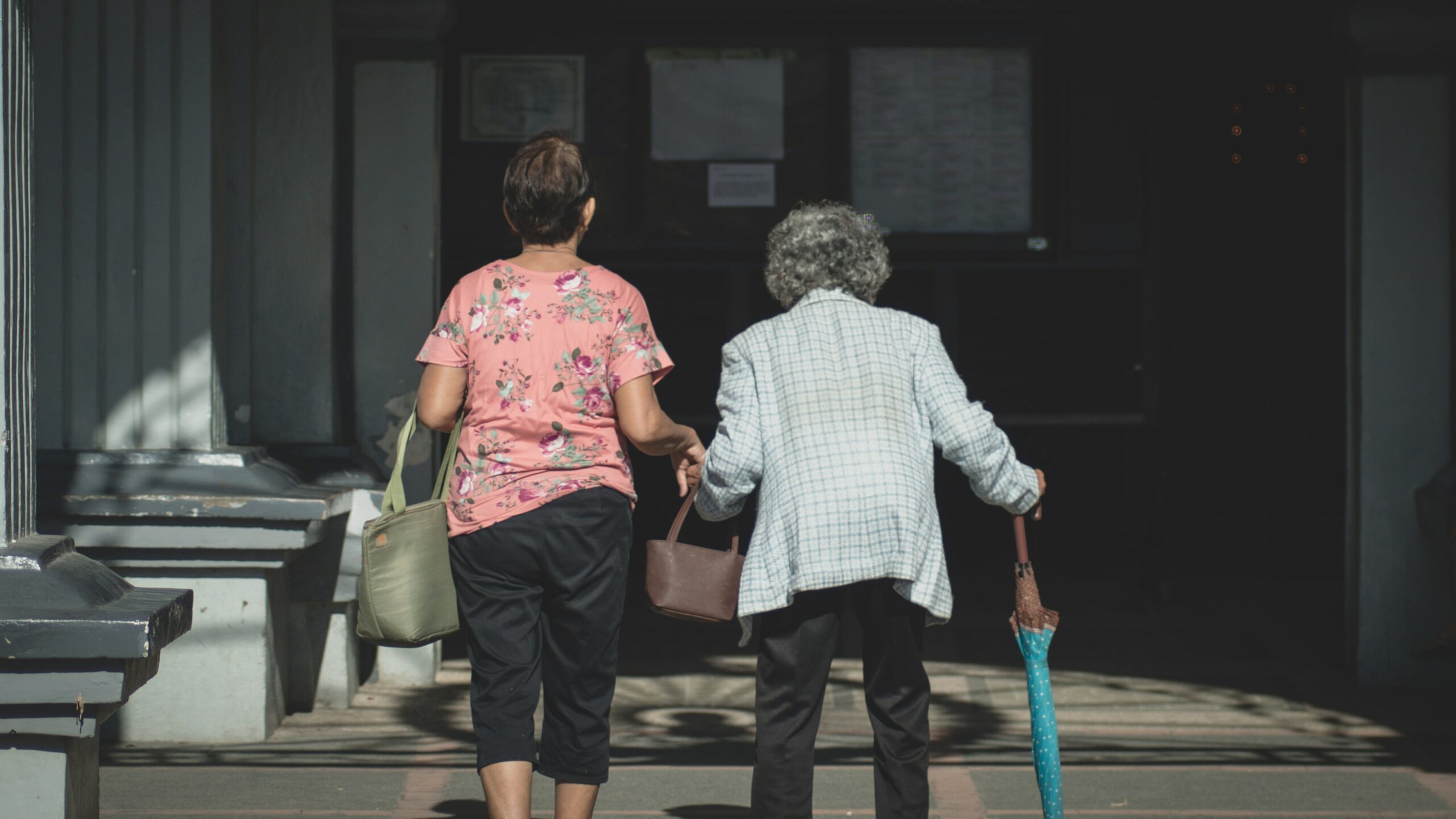 Photo of two older people walking away from the back.