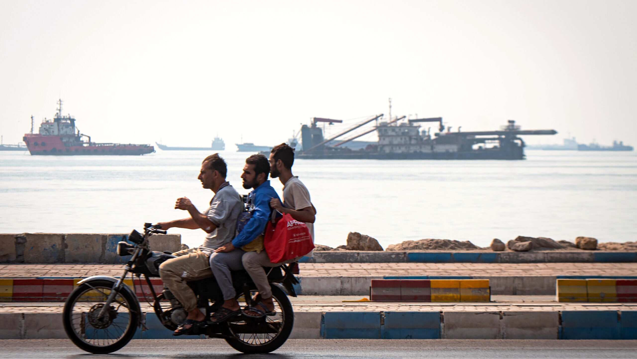 Photo of Iranian men riding a motorocycle along the coast line of the Strait of Hormuz.