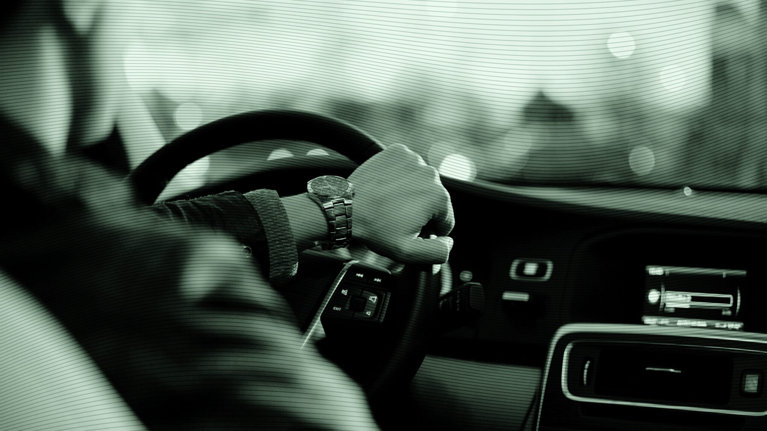 Photo of a person driving with their hand on the steering wheel